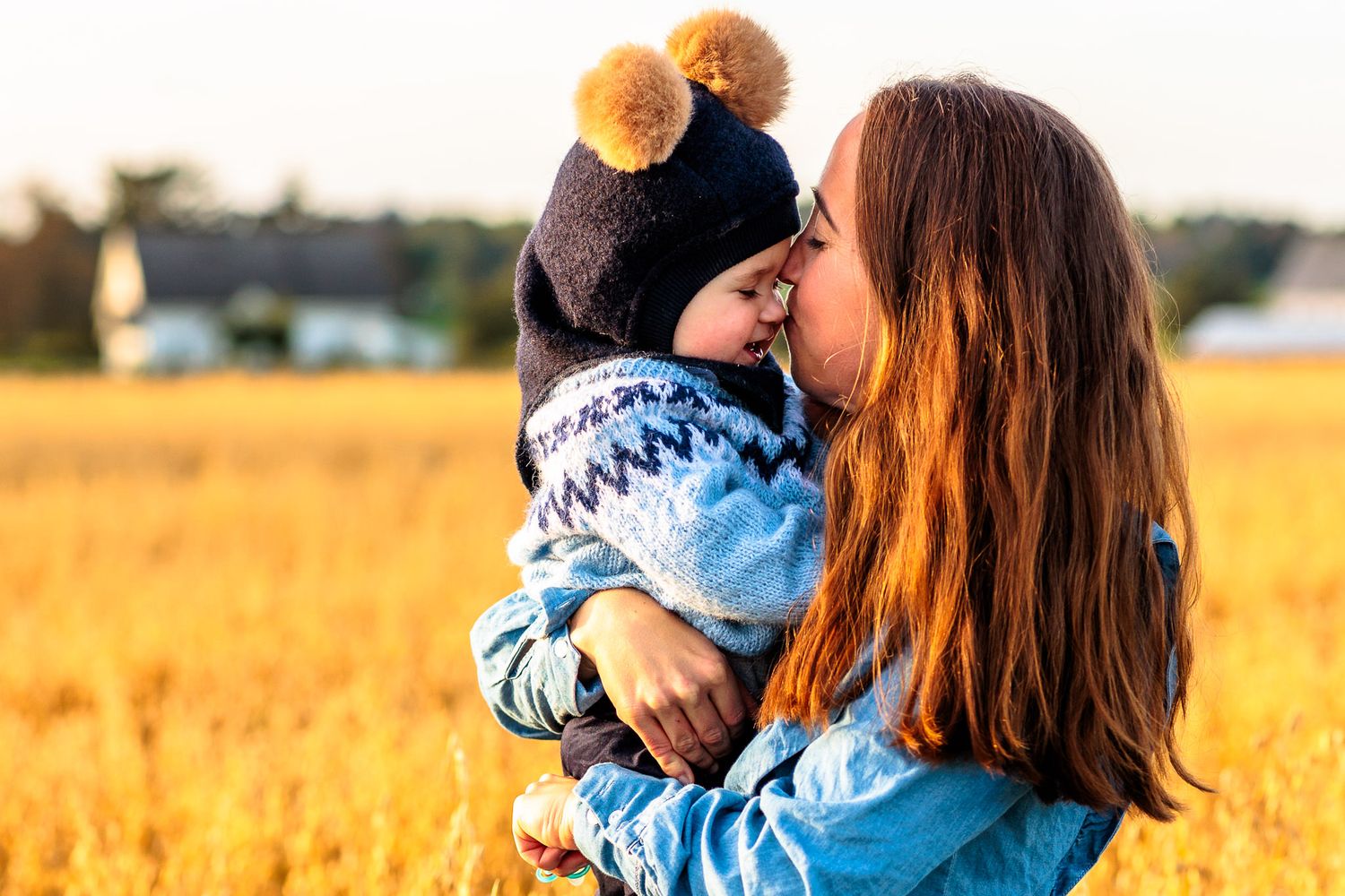 Mor og sønn gir hverandre kos i en kornåker i solnedgang på en familiefotografering på Malmheim.