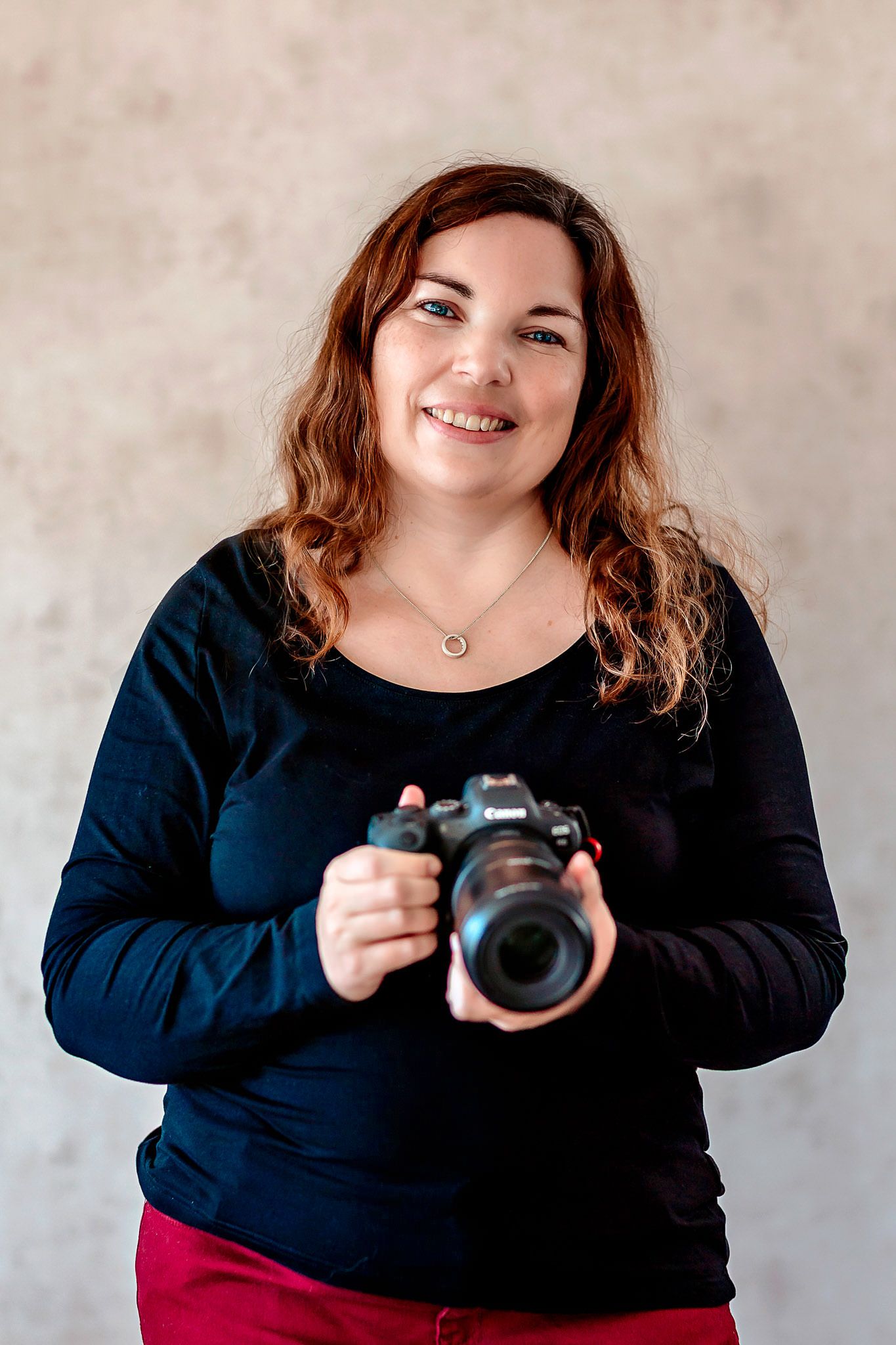 Selvportrett av fotograf Tone Ørstavik fra Ørstavik Foto i Rogaland. Hun smiler til kamera mens hun holder et Canon kamera i hendene.
