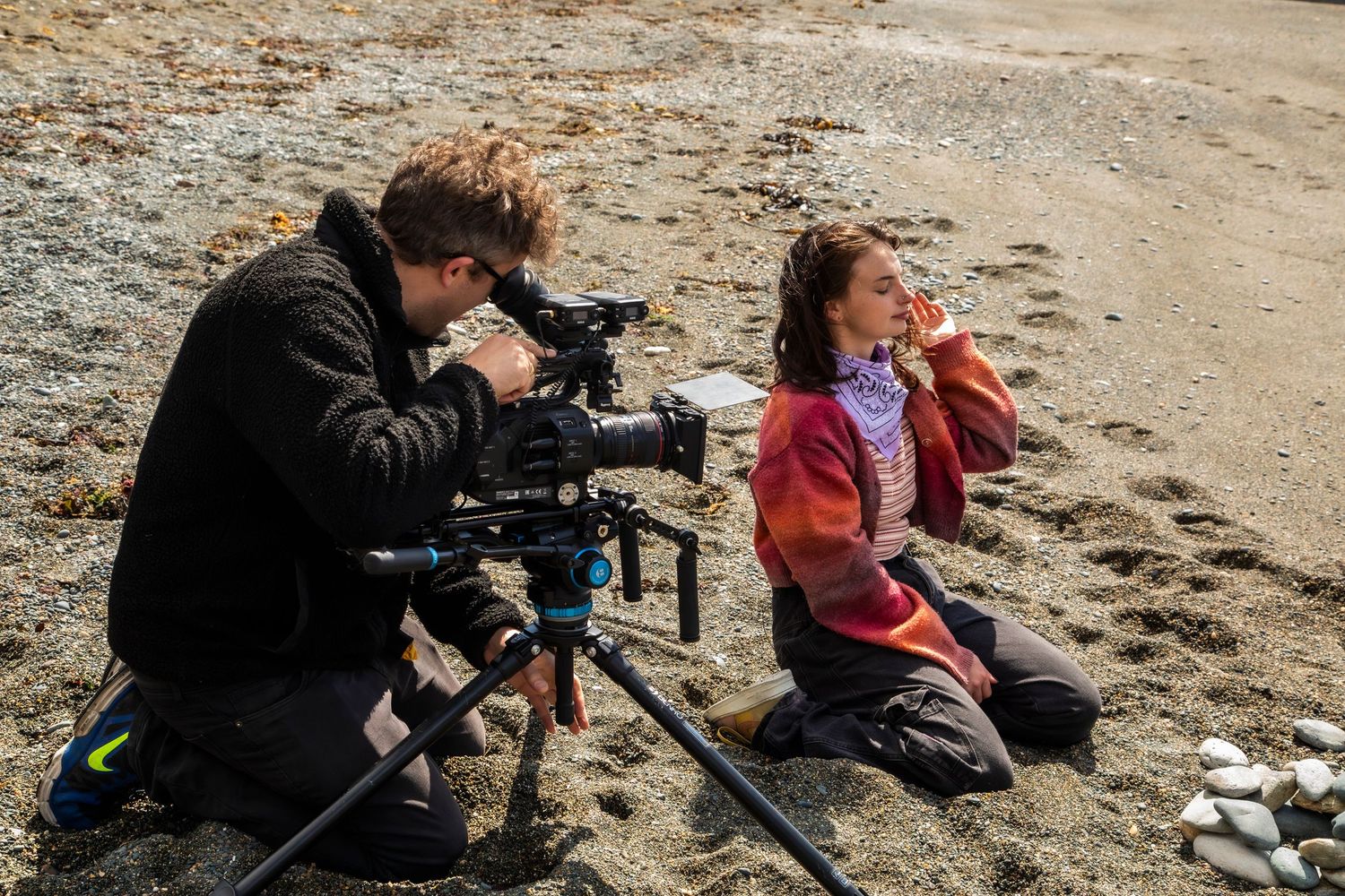 Photographers with cameras on tripods capturing images at a rocky beach during a photo shoot session.