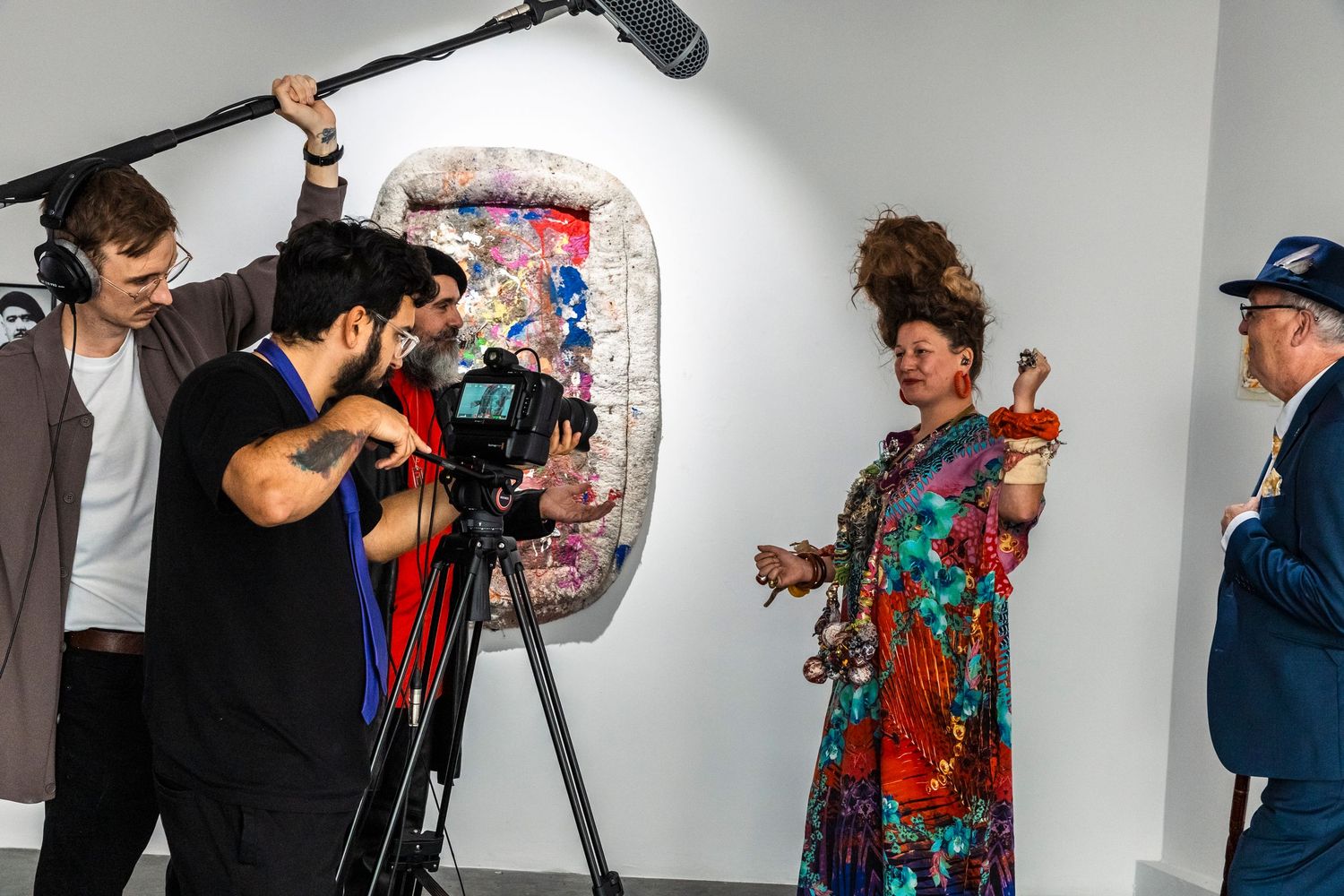 Behind the scenes photo of a film crew shooting a colorful fashion scene in a studio setting.