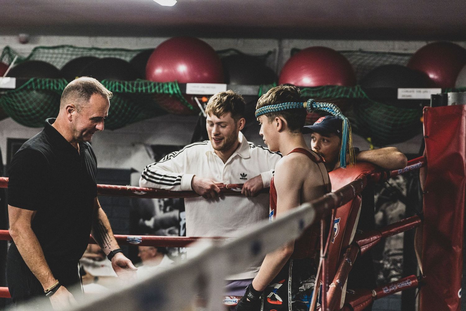 Boxing trainer wrapping fighter's hands in gym ring before match.