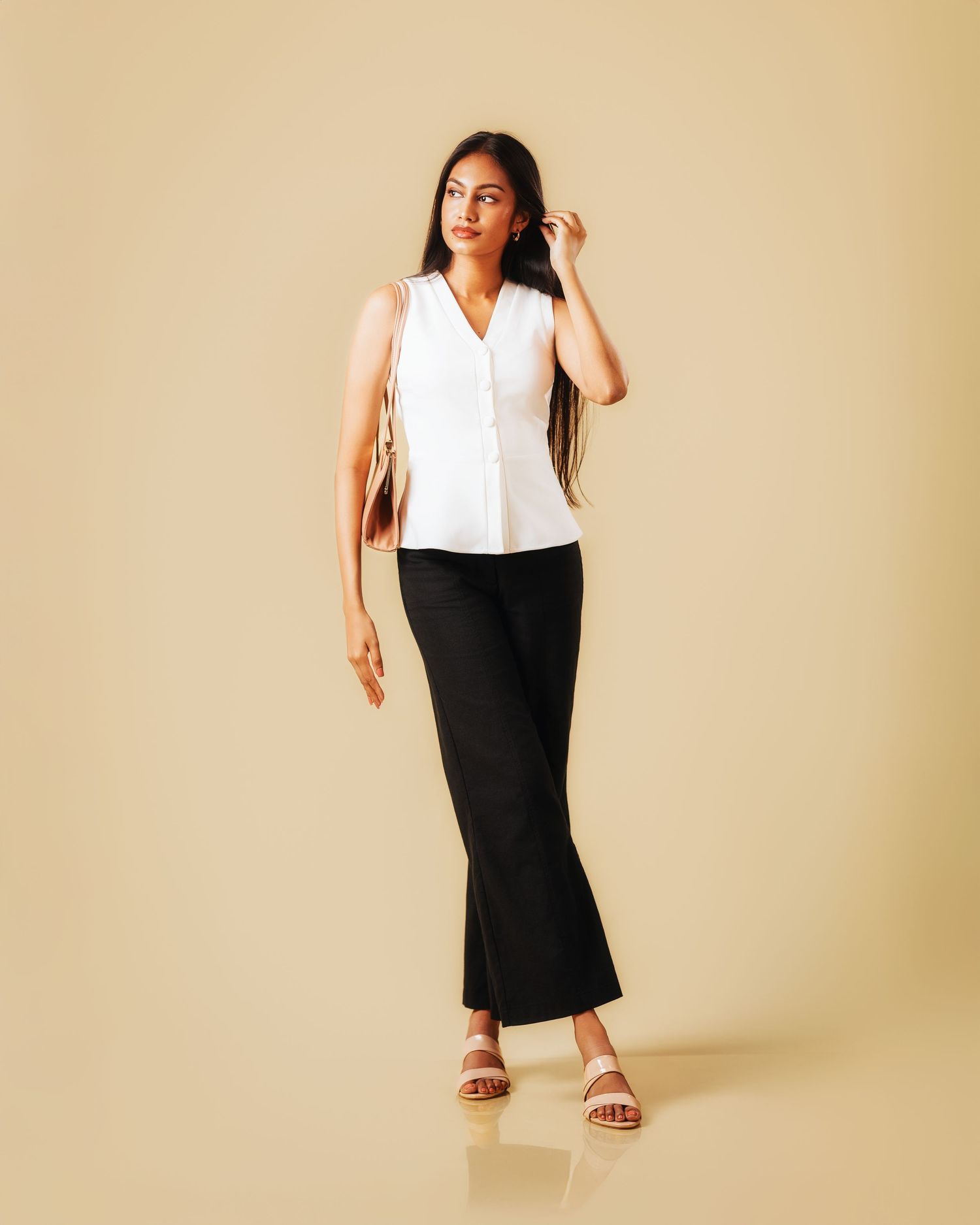 Model showcases a sleek black and white colorblock dress with sandals against a beige backdrop.