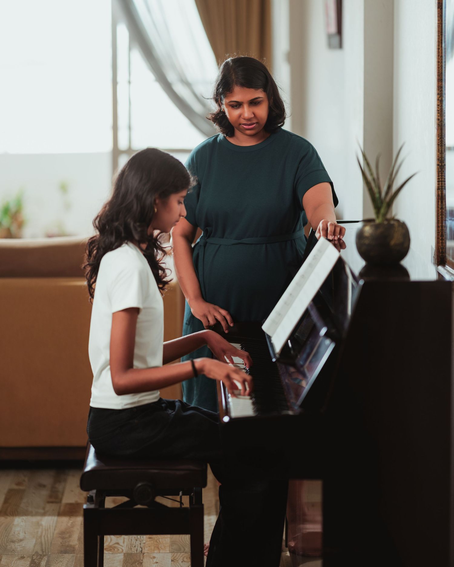 Piano lesson scene showing student and teacher interaction in bright indoor setting.
