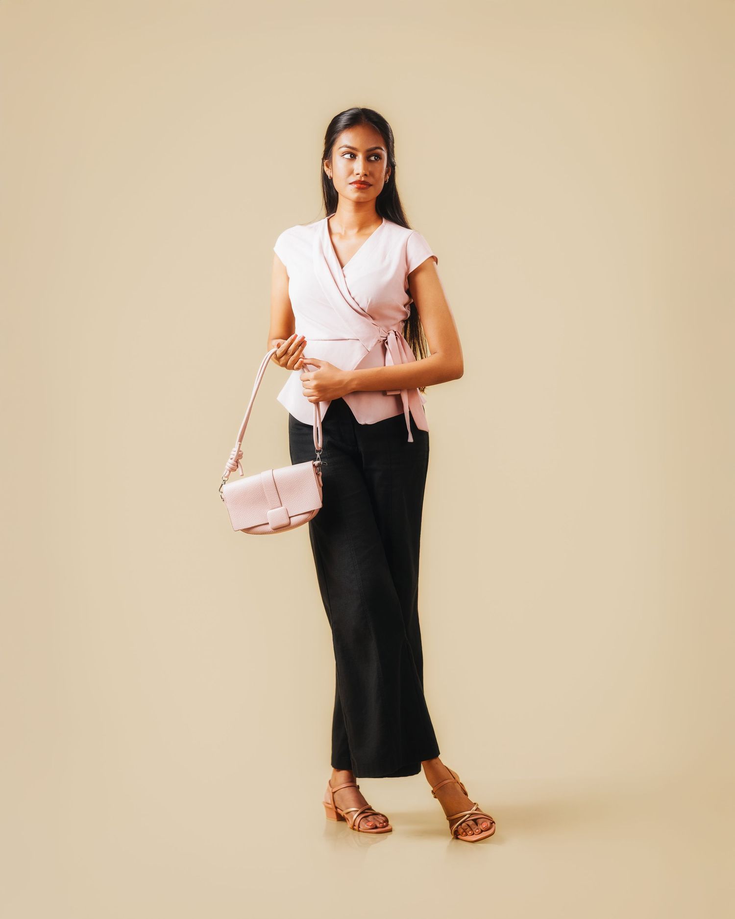 Model displays black and pink ensemble with matching accessories against beige background.