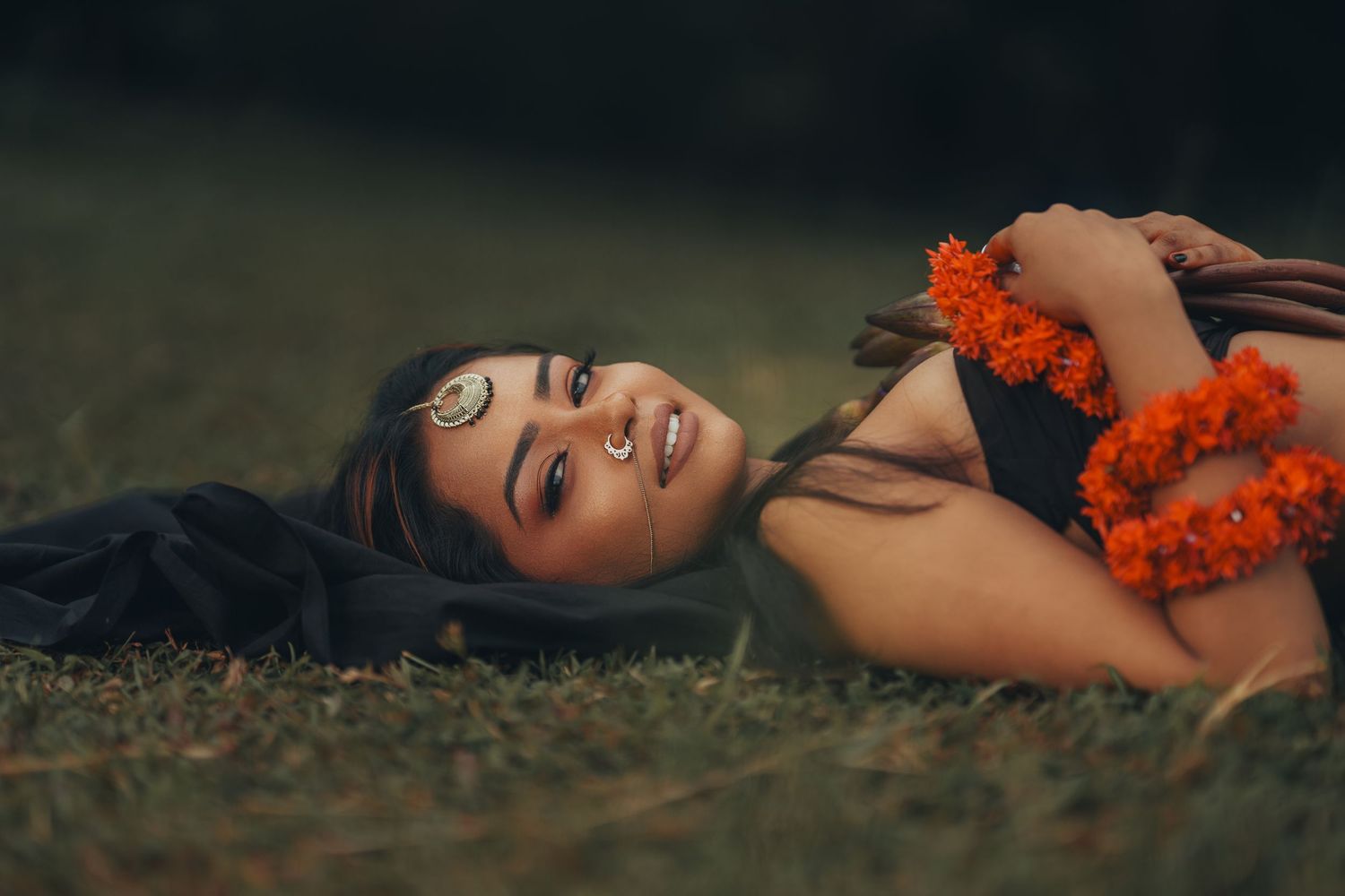 Artistic portrait with orange marigold flowers against a dark background creating a moody atmosphere.
