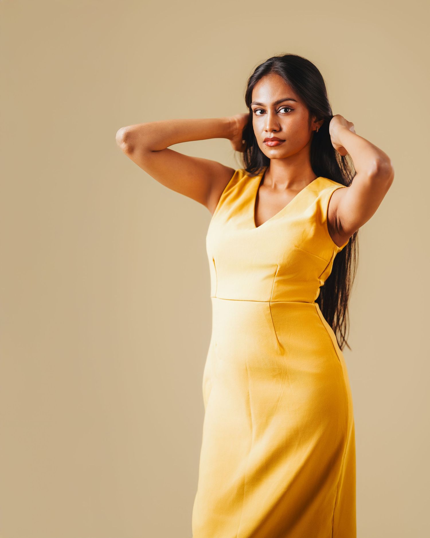 Woman models sunny yellow sleeveless dress in various poses against neutral backdrop.