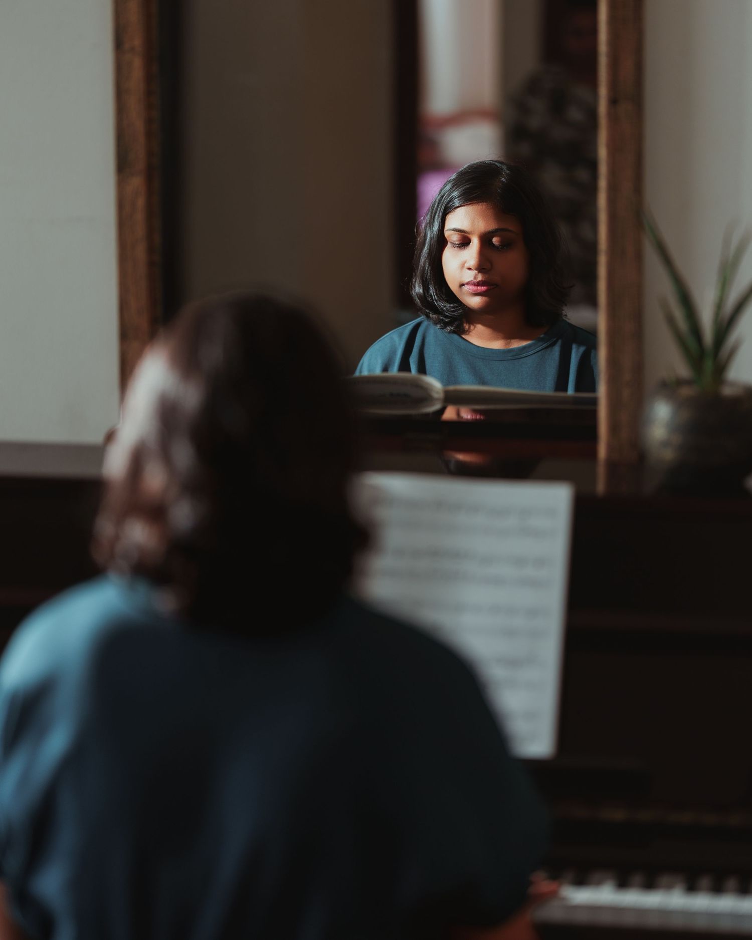 Moody indoor scene of piano practice in low lighting.