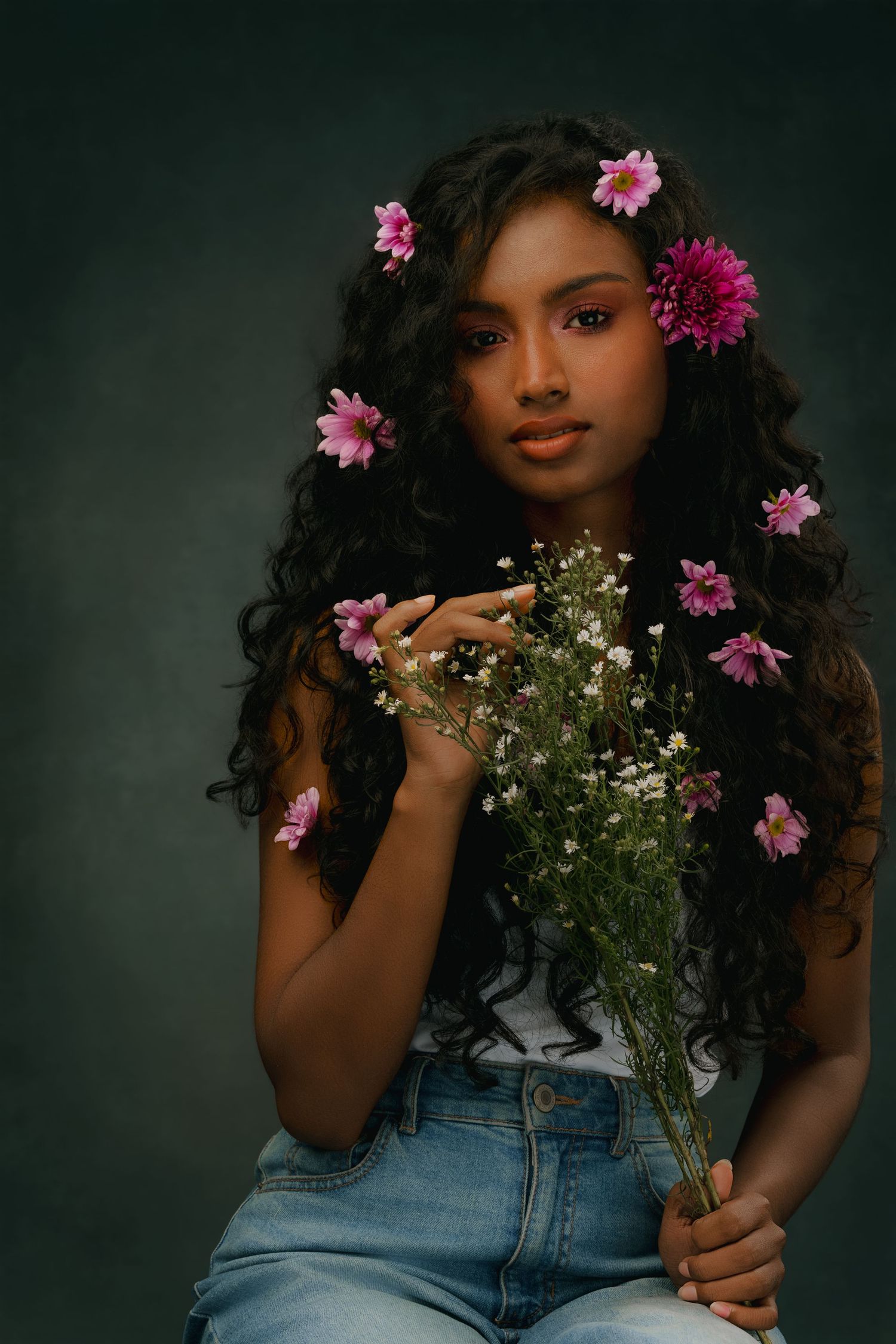 Studio portrait with pink flowers and baby's breath bouquet against dark background.
