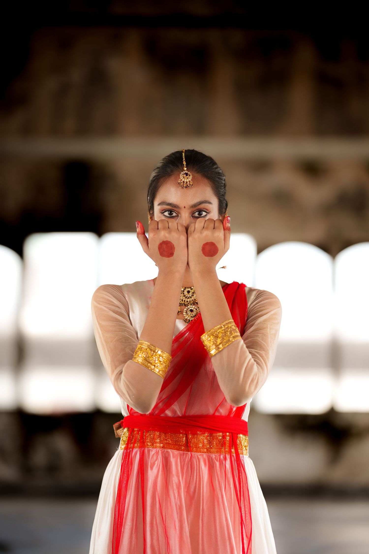 Artistic portrait in red dress with traditional Indian jewelry and makeup.