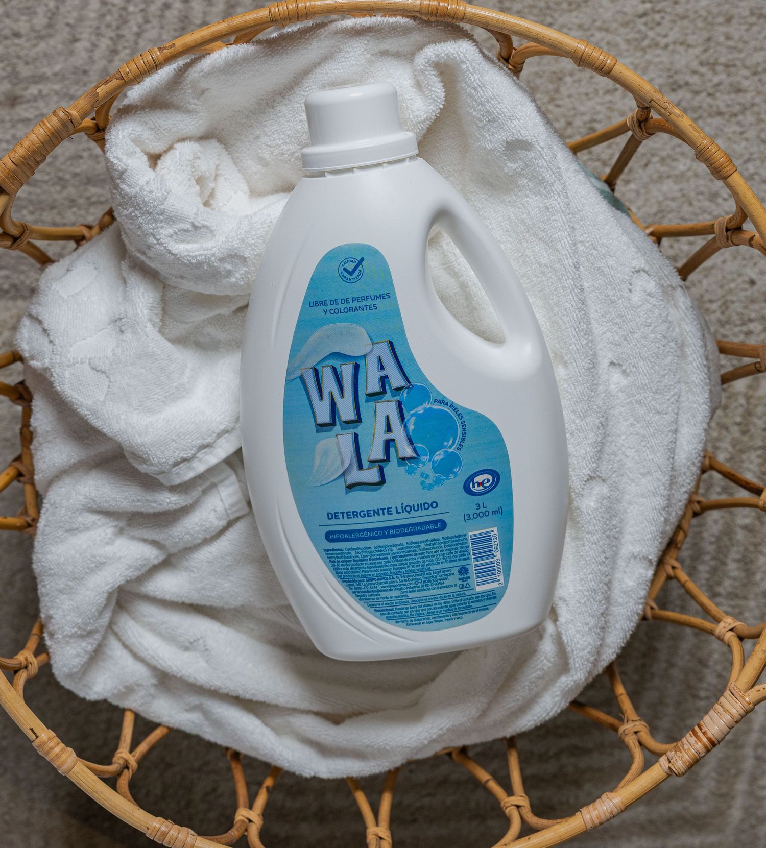Wala liquid laundry detergent bottle placed on white fluffy towels in a wicker basket.