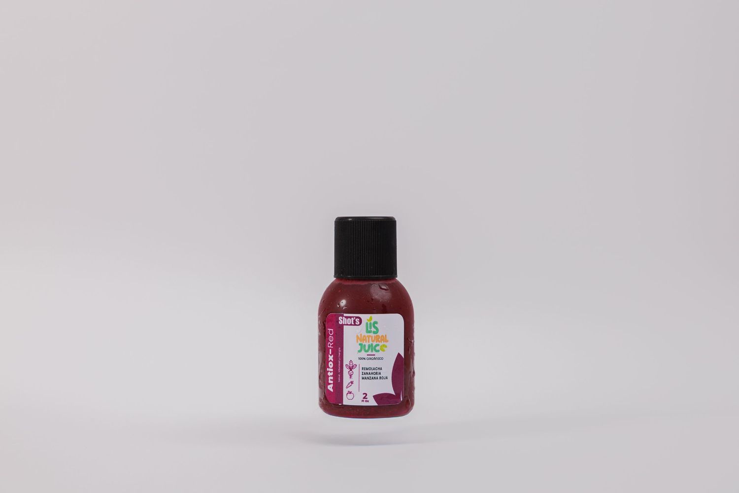 Small pink travel-size hair care bottle with black cap and colorful label on white background.