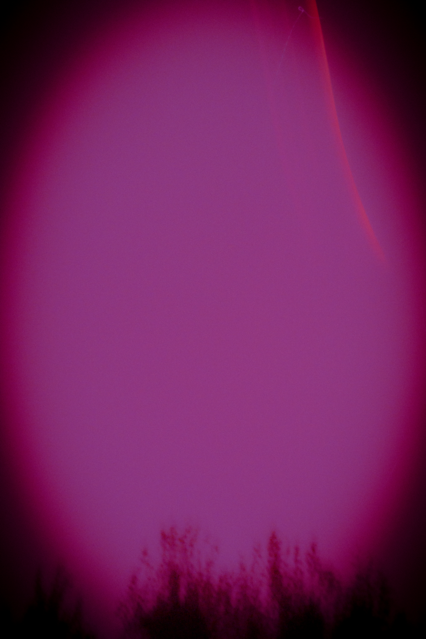 Pink and purple aurora borealis glow illuminates the night sky with dark foreground.