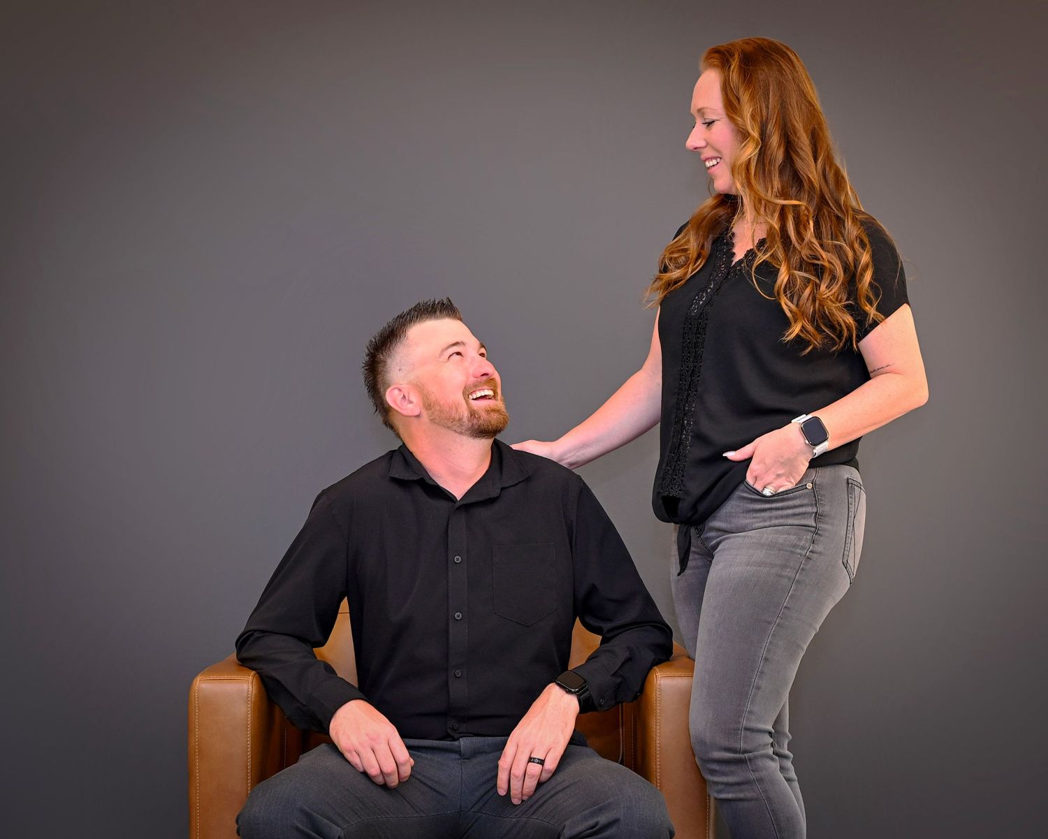 A series of candid studio photos showing two people interacting and laughing together against a grey backdrop.