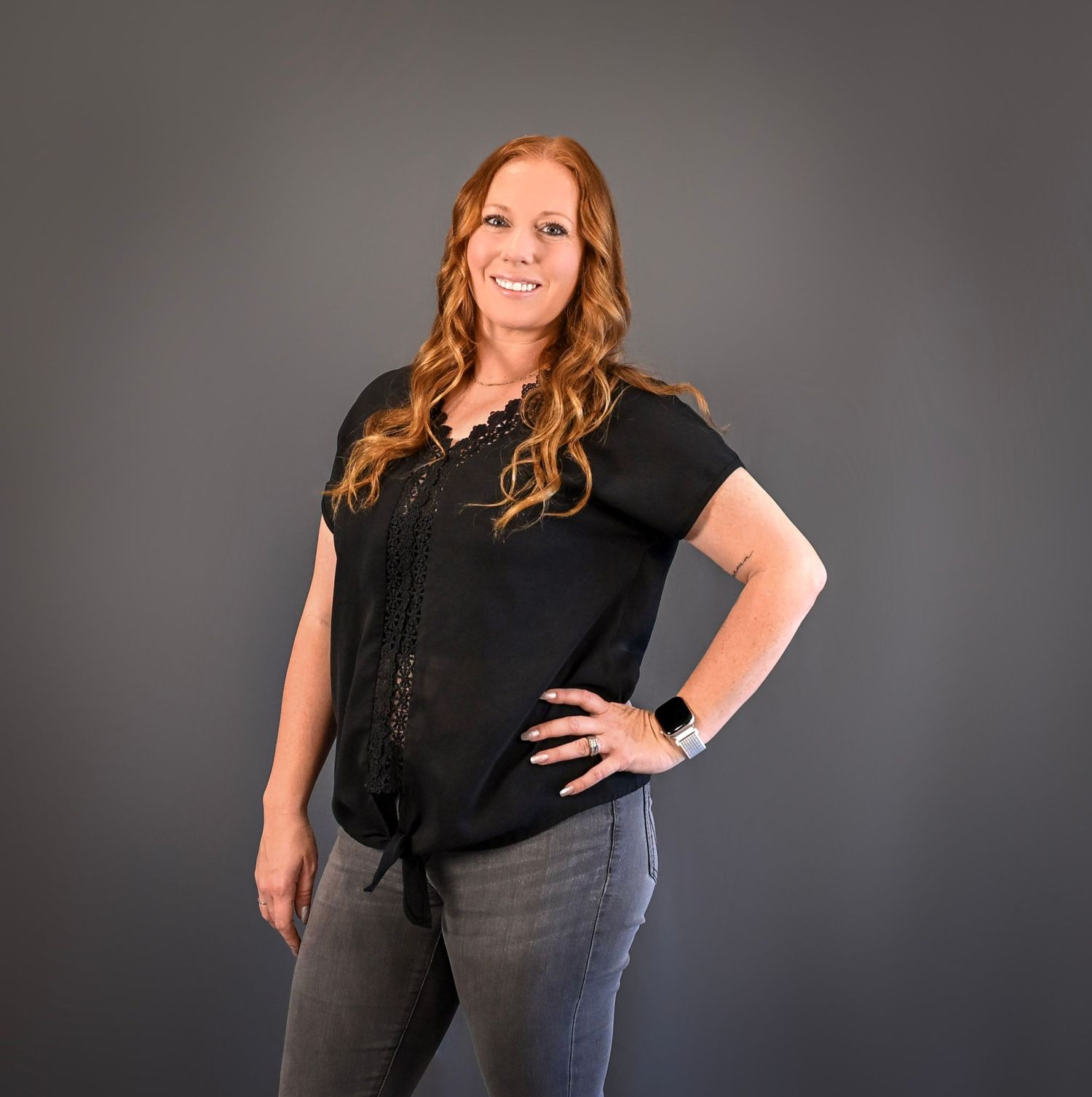 Woman in black outfit poses confidently against dark background in fashion photoshoot series.