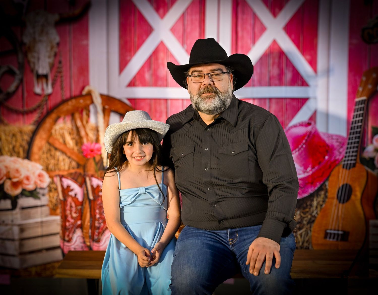 Country western themed portrait session against red barn backdrop with vintage decor.