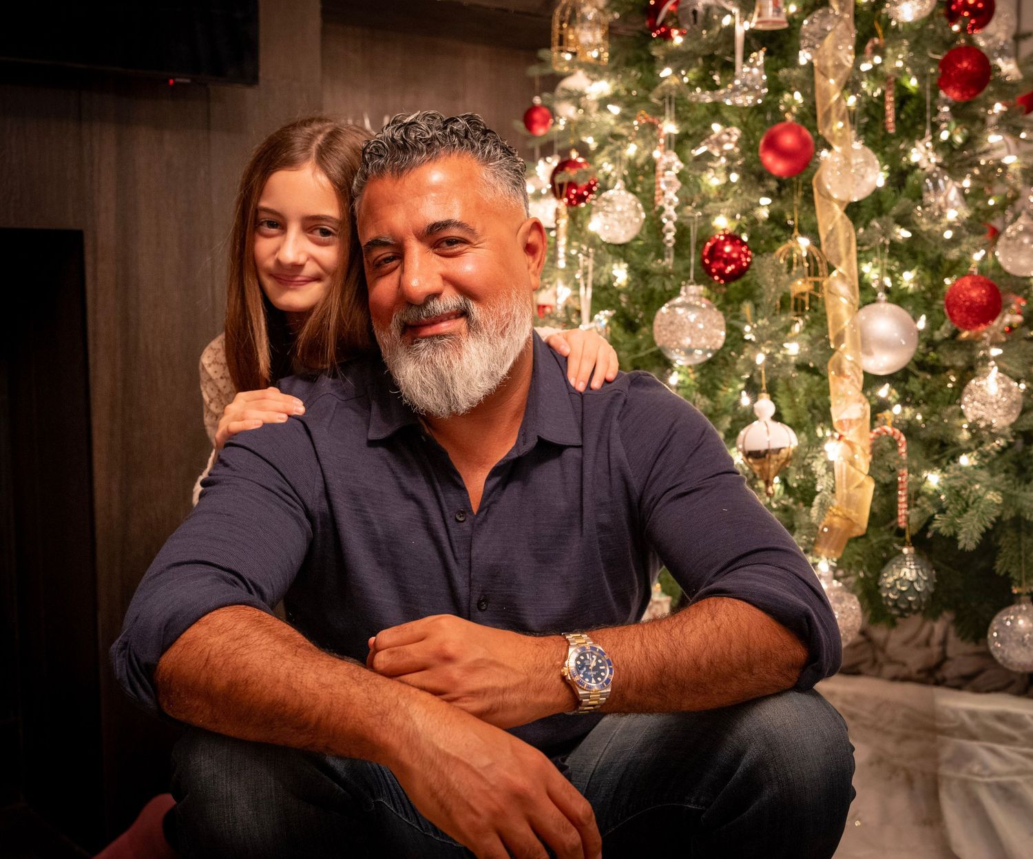Holiday portraits in front of decorated Christmas tree with twinkling lights and ornaments.