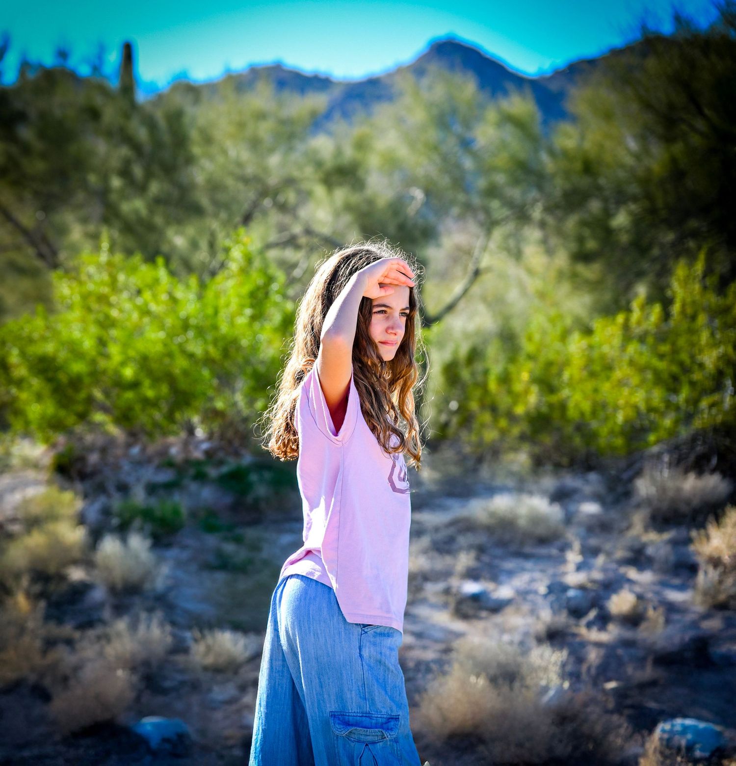 Desert mountain photoshoot with vibrant turquoise sky and natural vegetation.