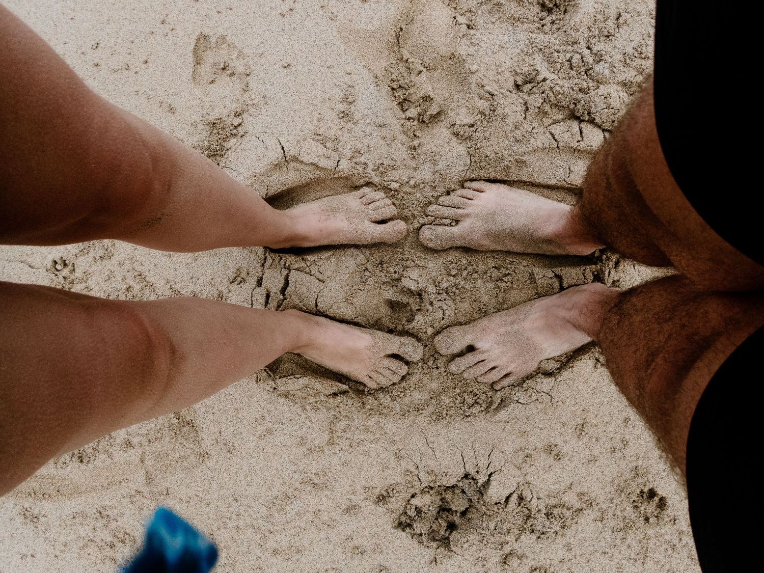 Feet and legs on sandy beach with water ripples.