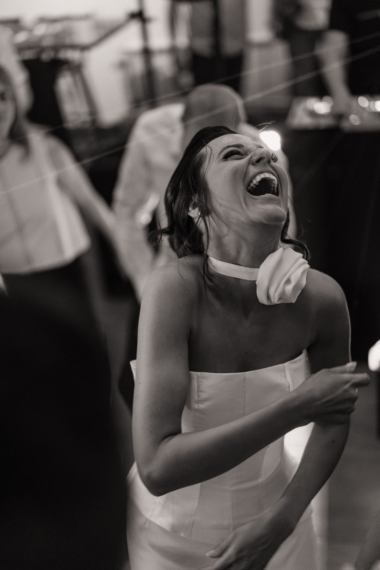 Woman in white dress laughing joyfully during a celebration.