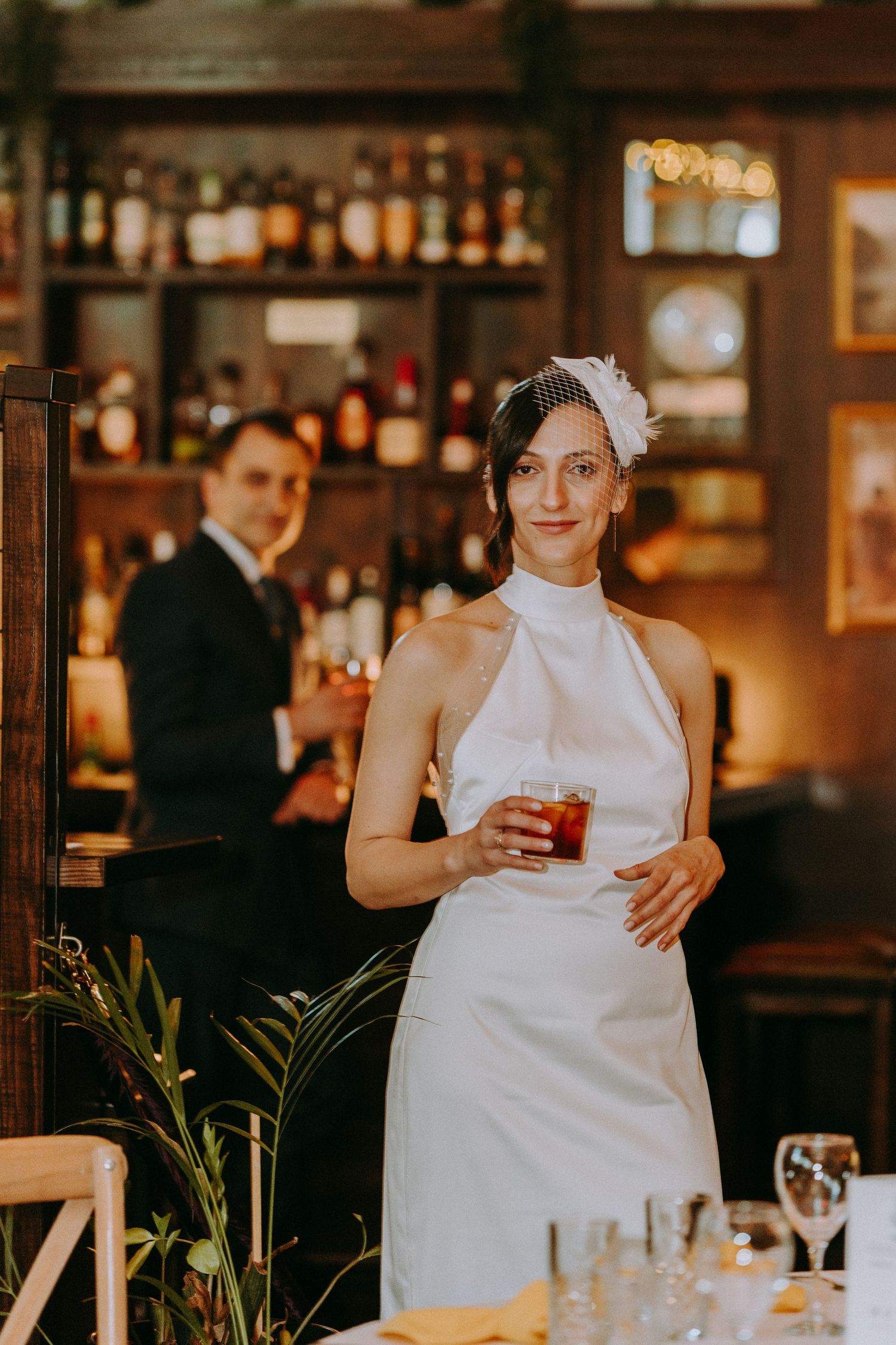 Reception venue with warm lighting and bar setting as bride enjoys celebration.