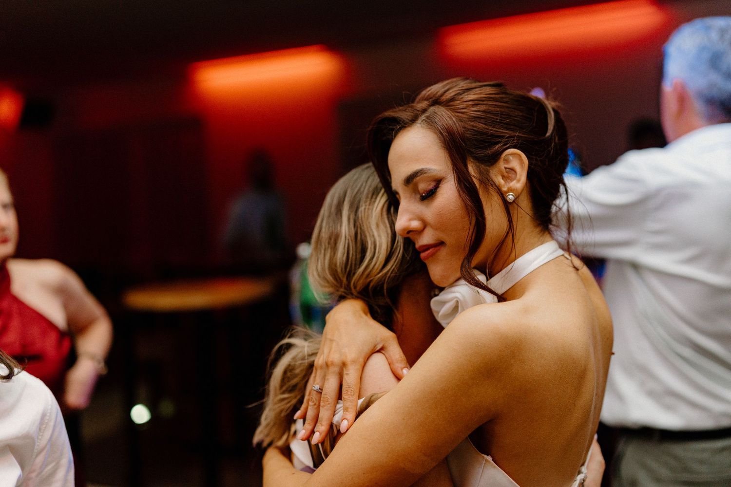Couples embracing on a dance floor with red ambient lighting.