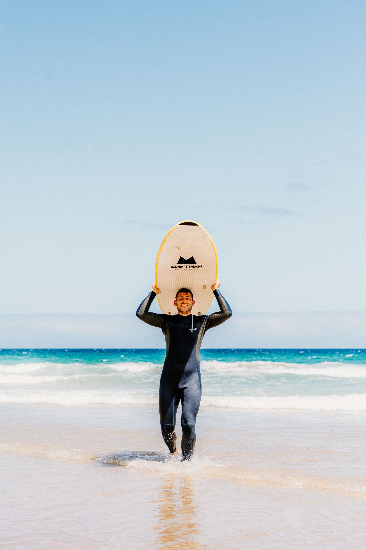 A series of photos showing a surfer walking along a beach carrying a white surfboard.