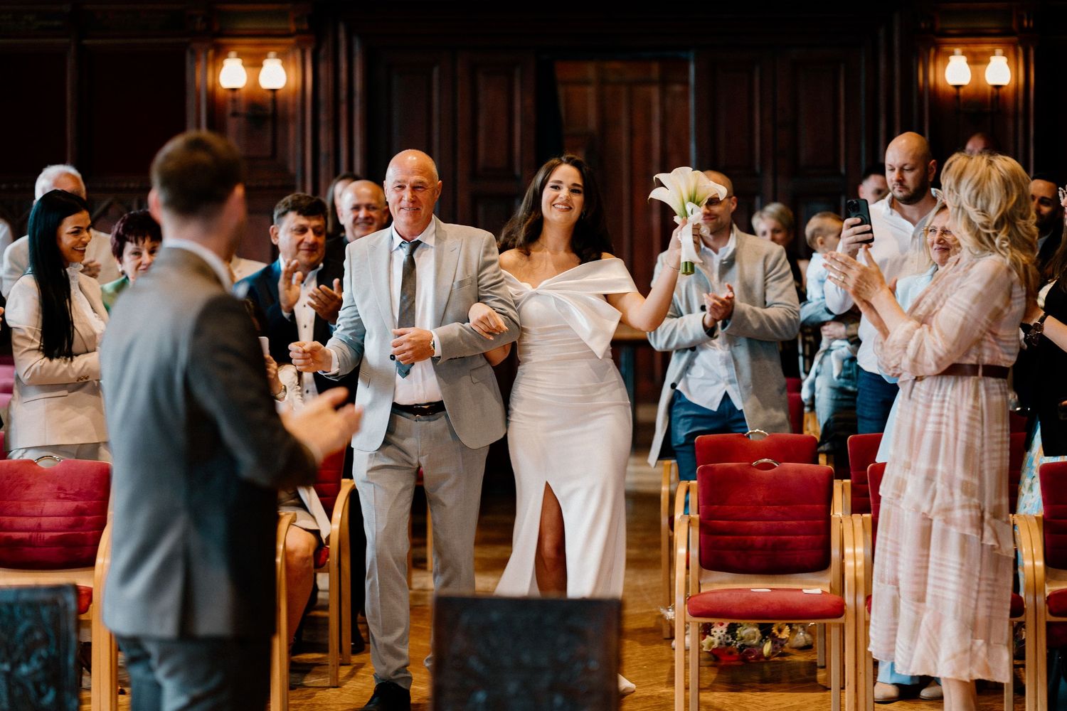 Wedding guests celebrating and raising glasses during a reception in an ornate indoor venue.