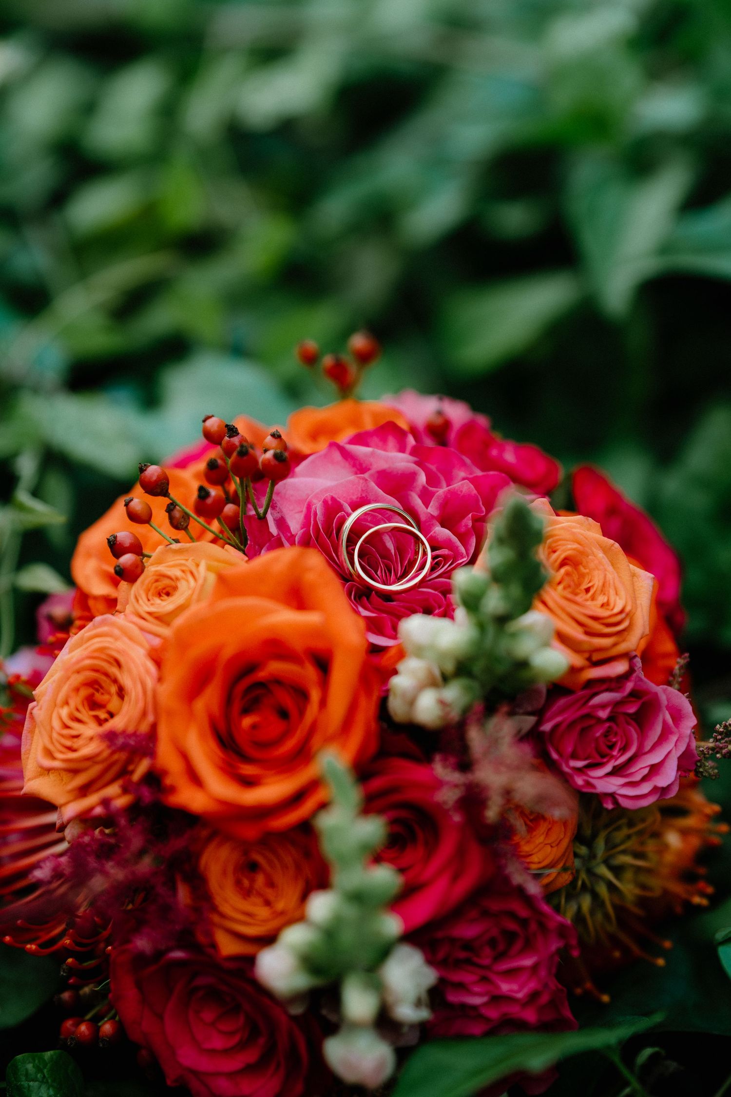 Vibrant wedding bouquet featuring orange and deep pink roses with delicate white accents.