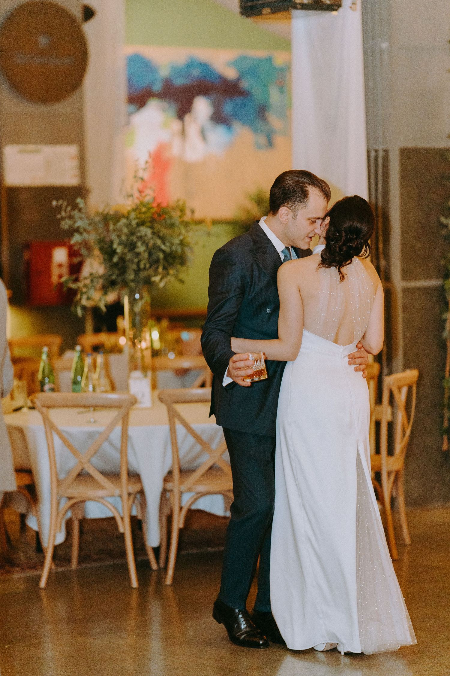 First dance in wedding reception venue with rustic decor and natural lighting.