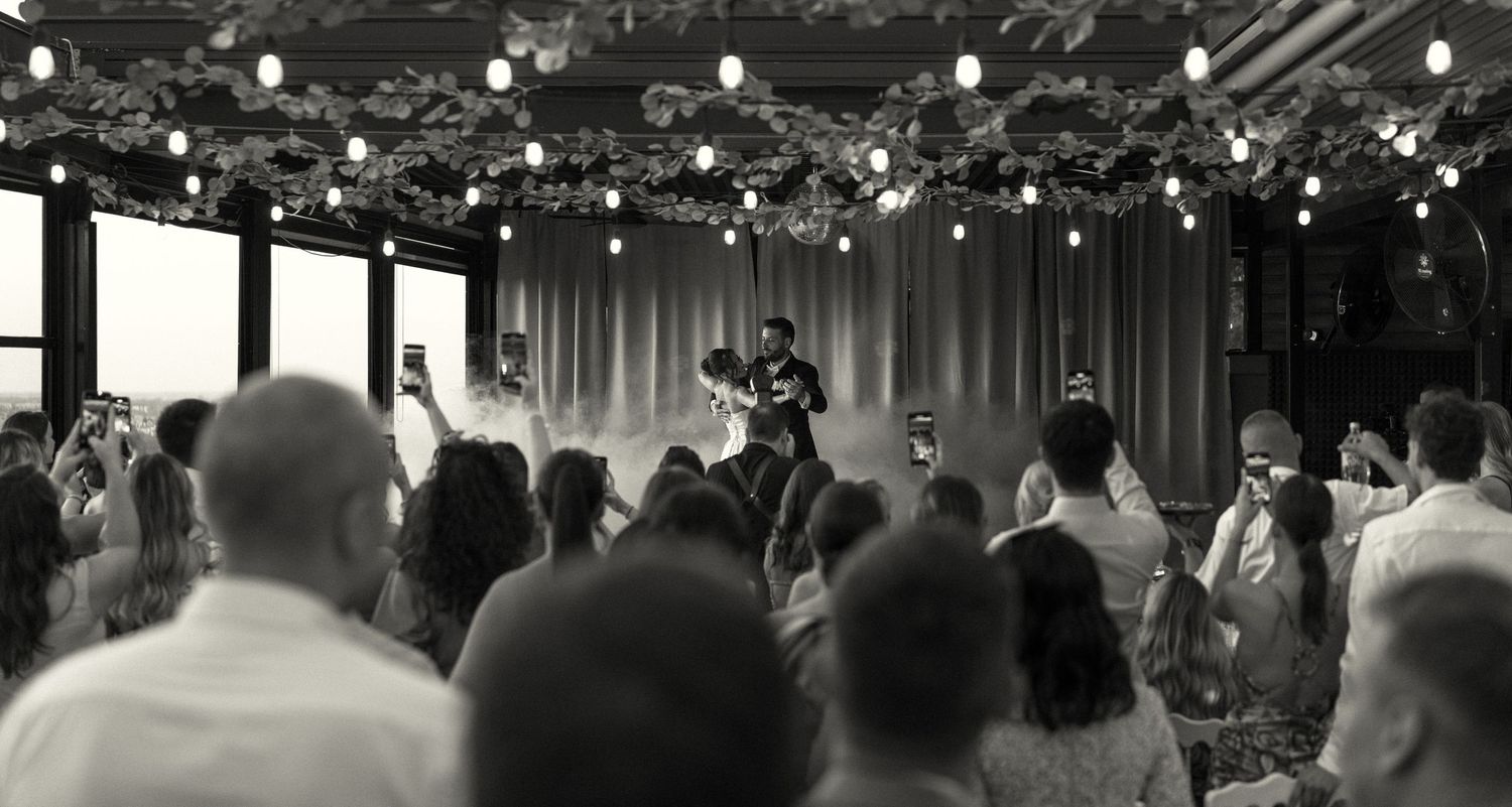 Black and white wedding reception scene with string lights and dancing guests.