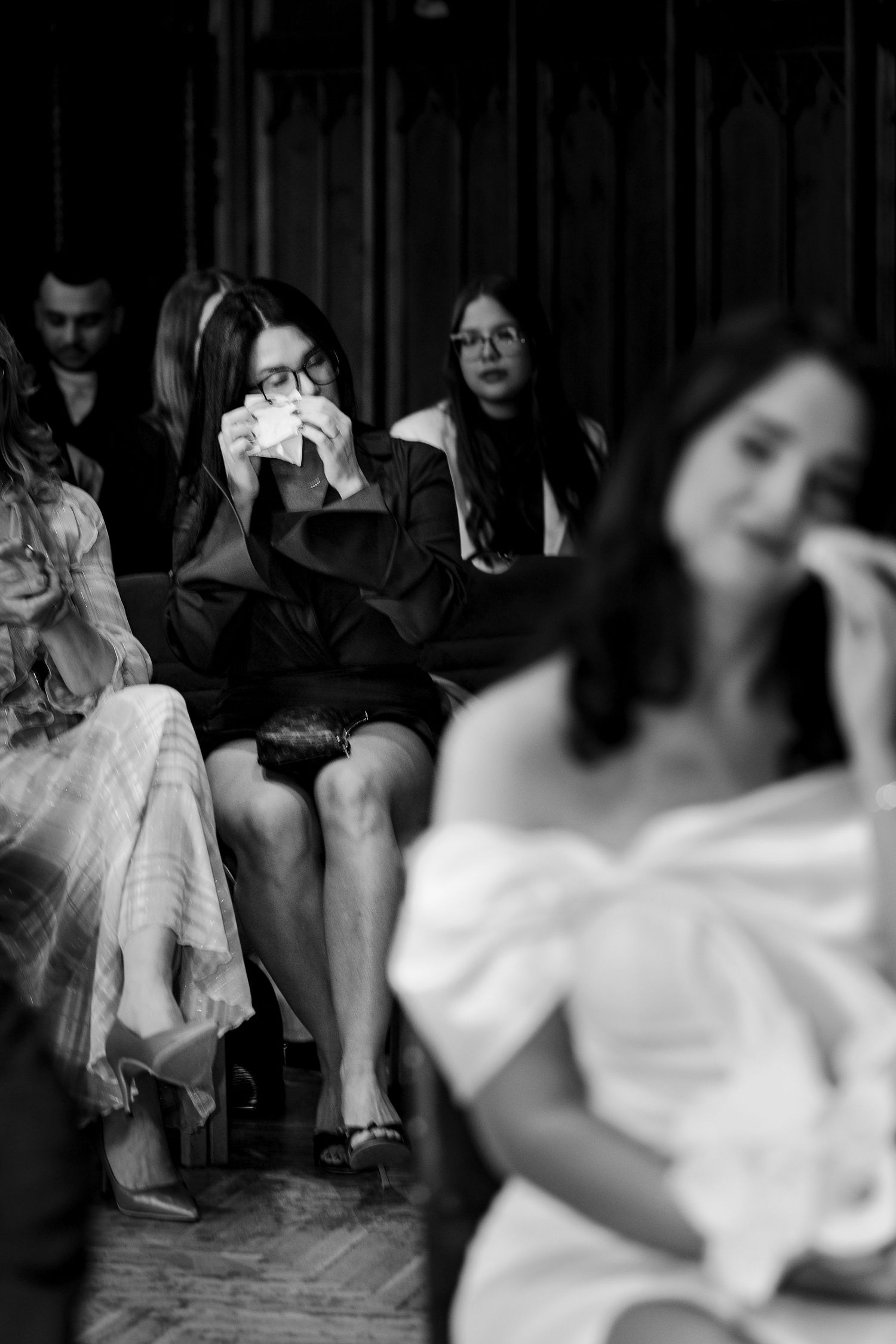 Black and white photo of emotional wedding guests wiping tears during ceremony.