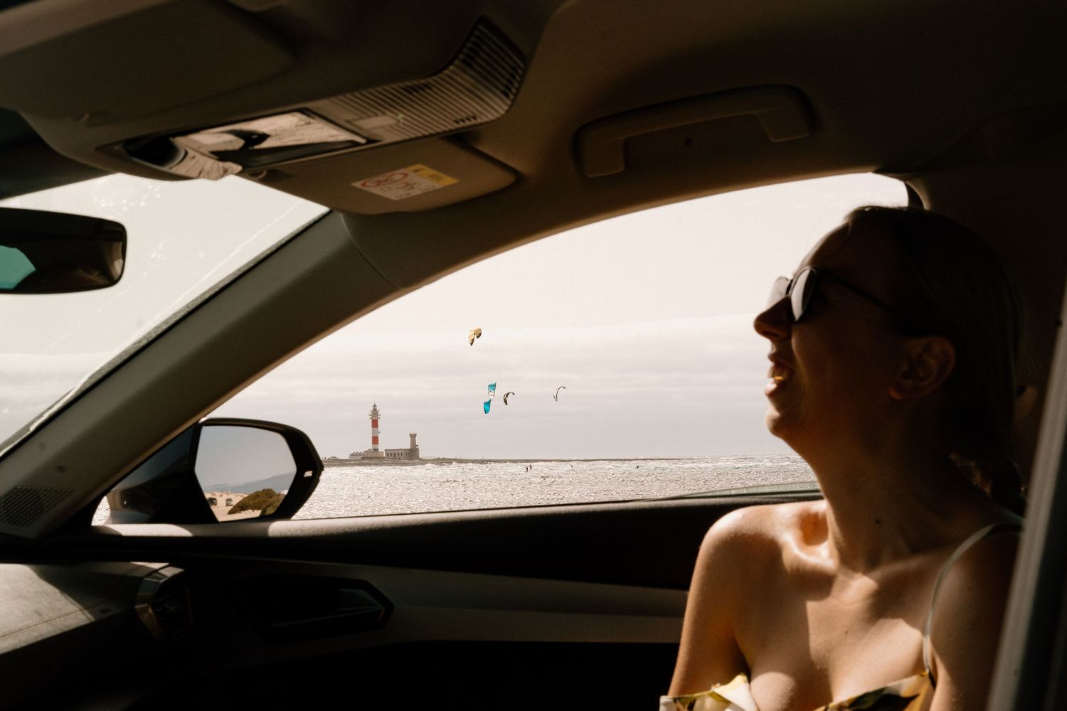 Interior view of a car dashboard with beach scenery visible through the windshield.