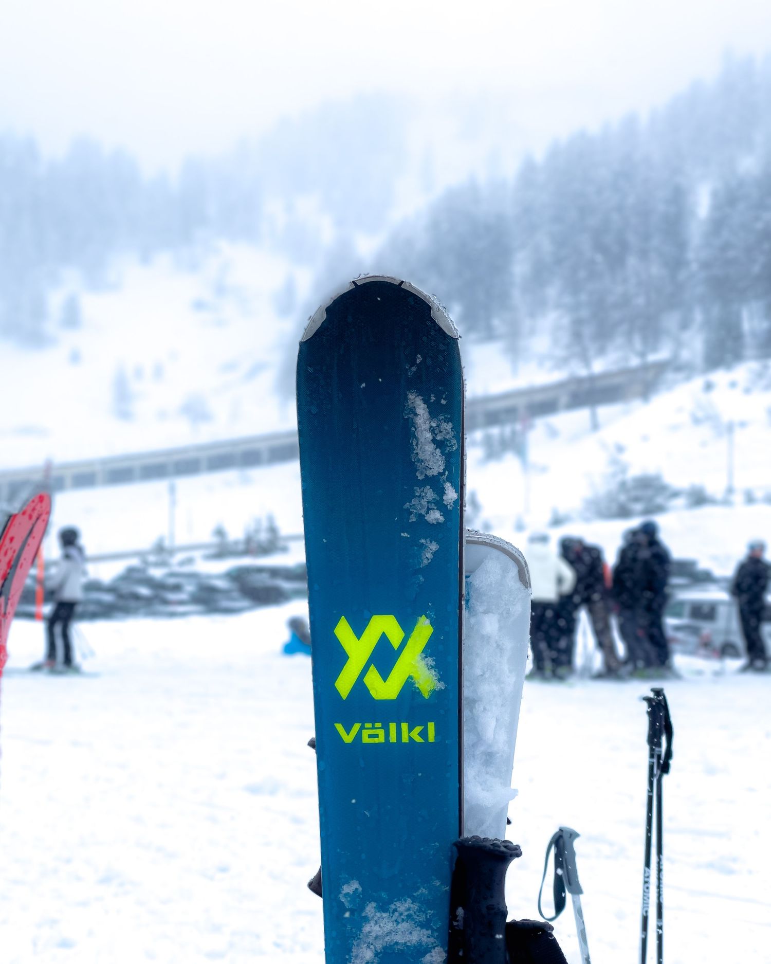 Volkl ski equipment lined up in snowy mountain terrain.