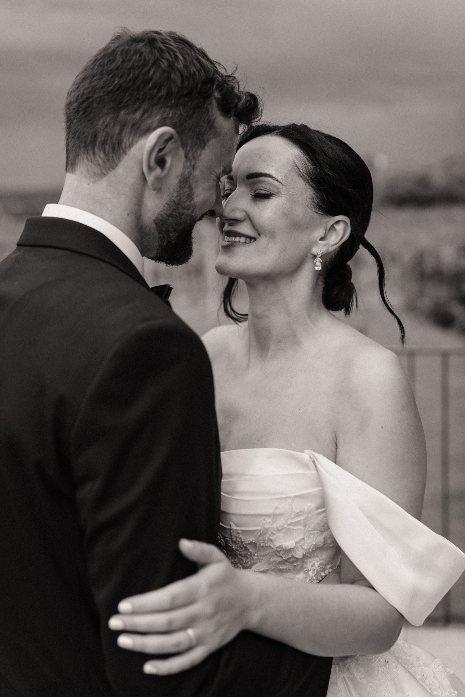 Black and white photo of a smiling bride and groom sharing an intimate moment at their wedding.