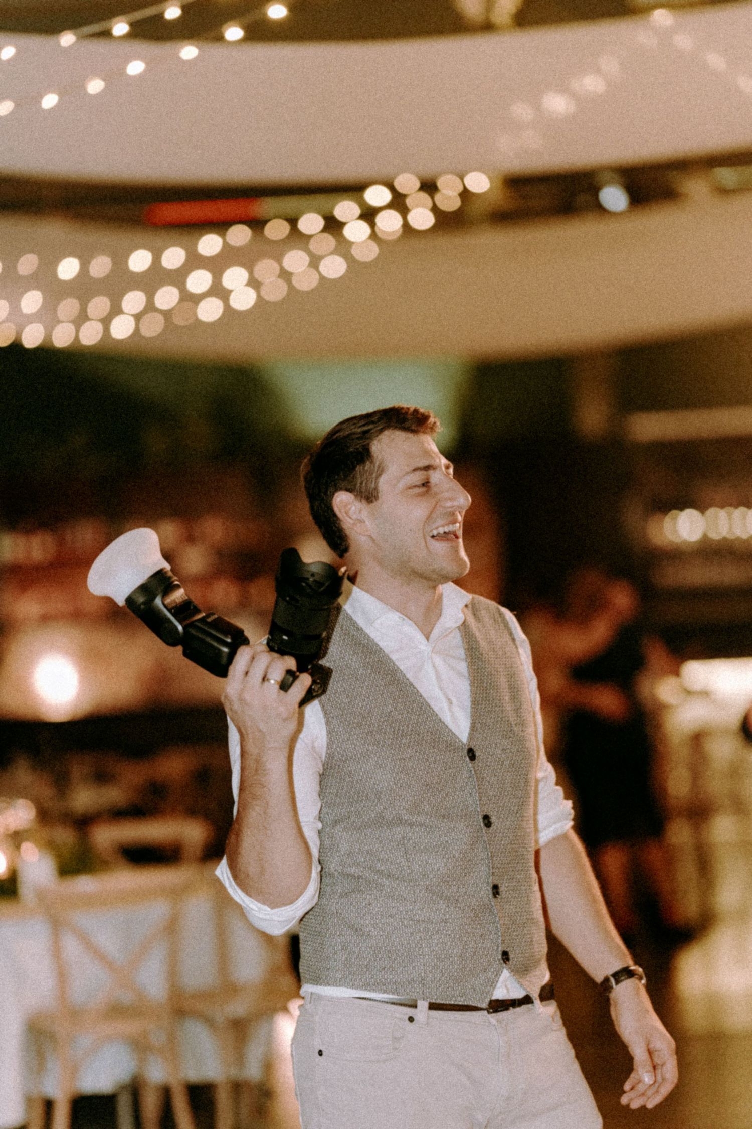 Event photographer in action under string lights at an indoor venue.
