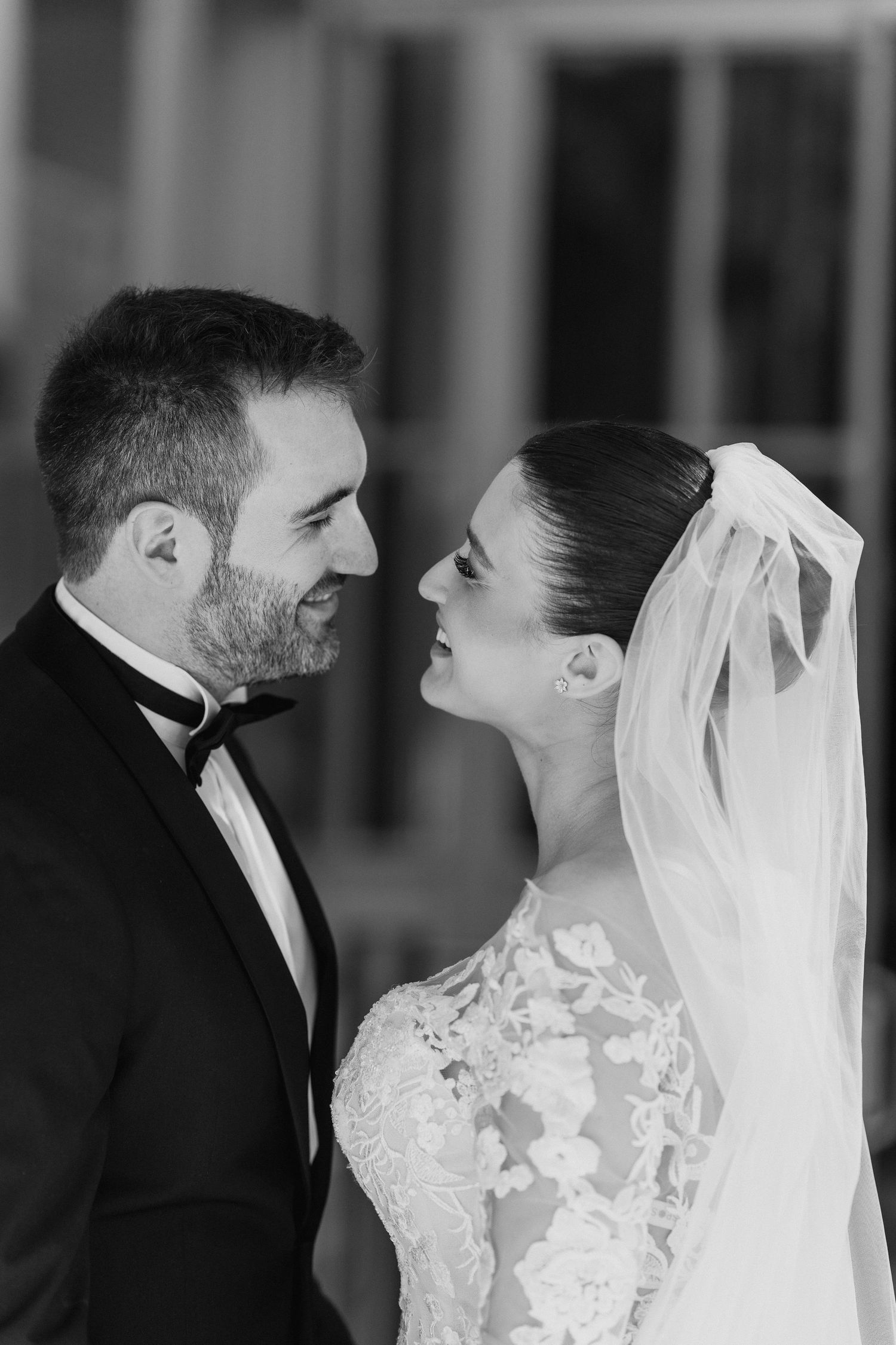 An elegant black and white portrait of newlyweds gazing at each other with joy.