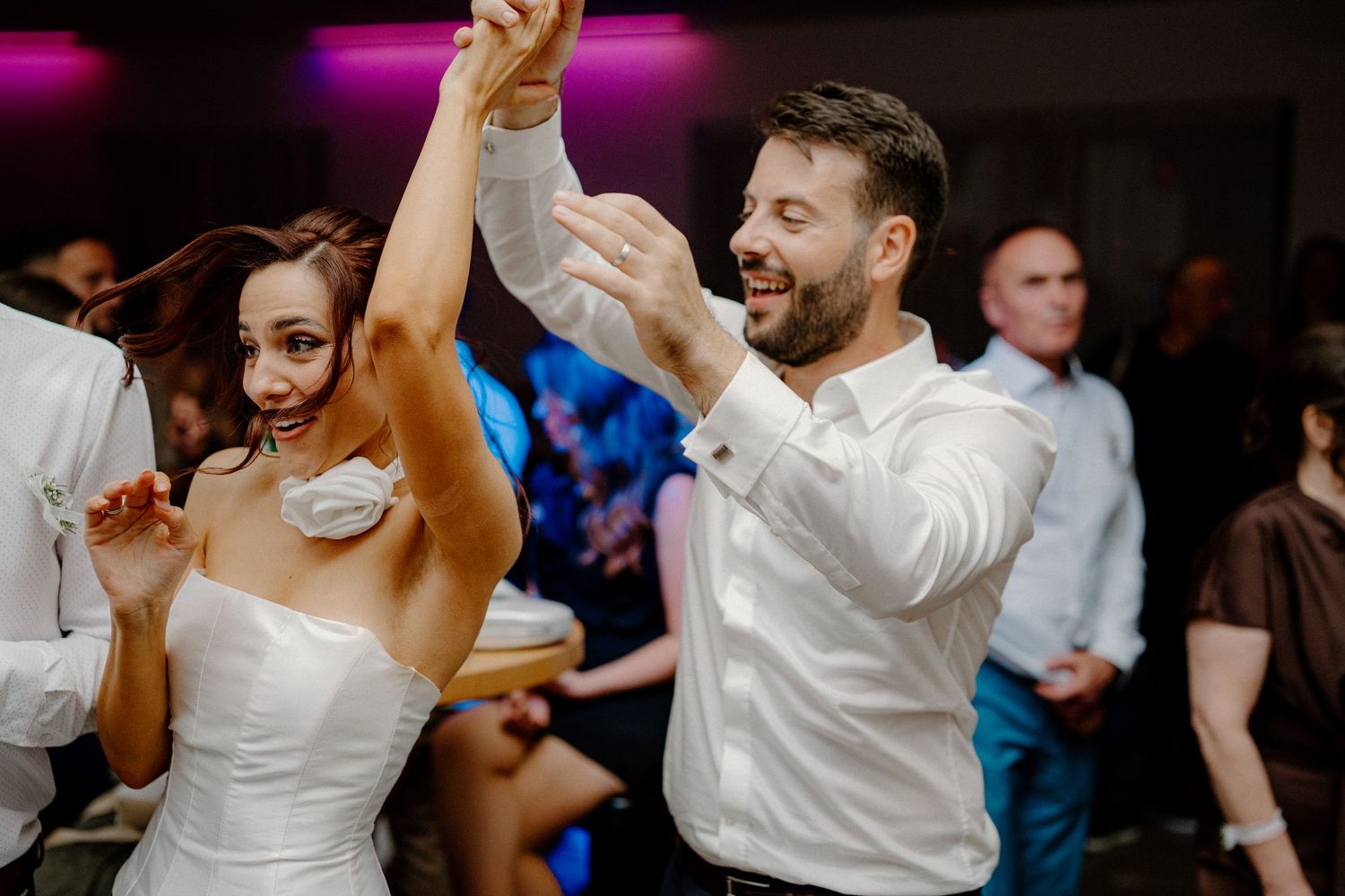 Party guests dancing and celebrating under colorful mood lighting.