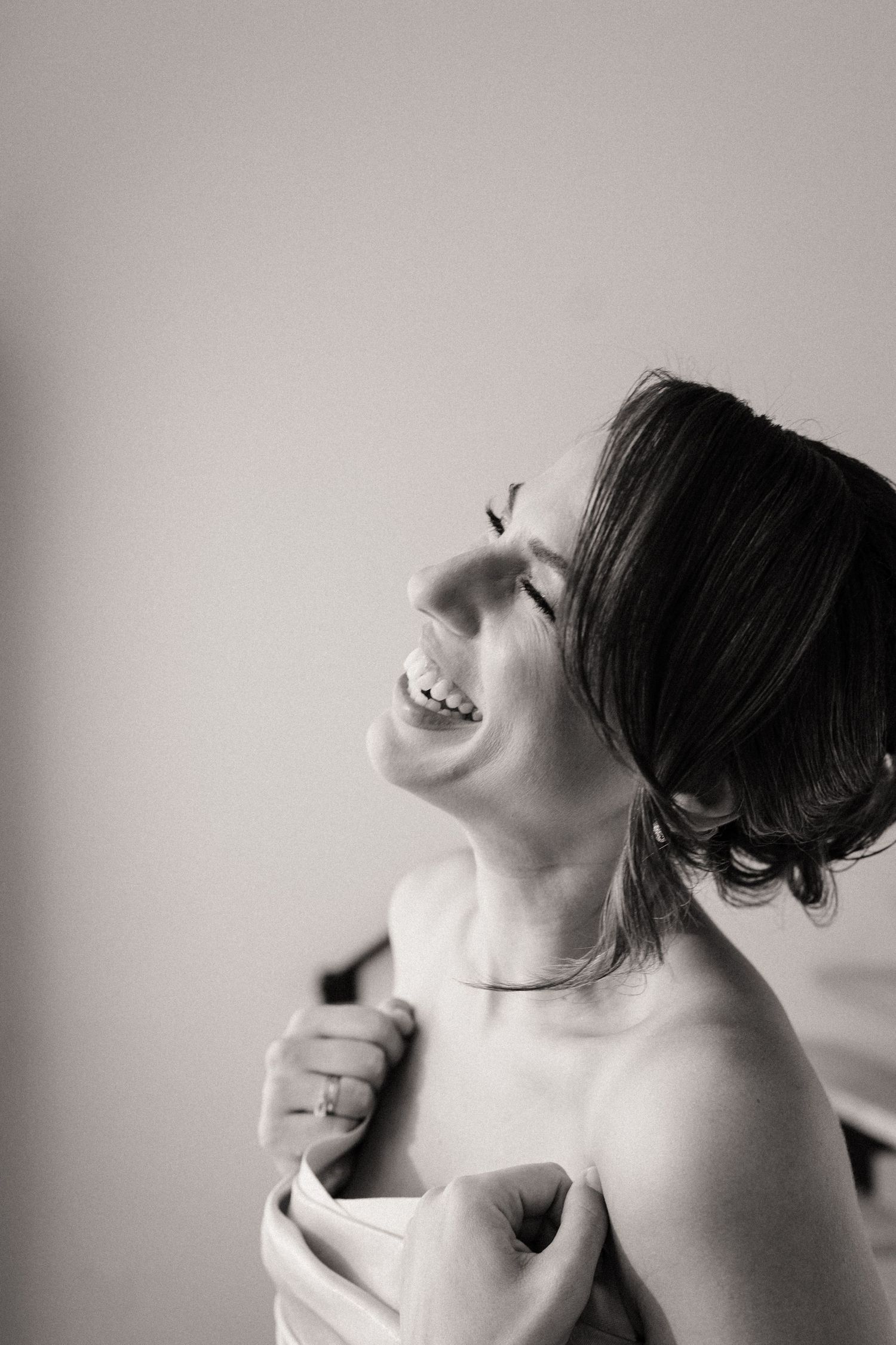 Black and white portrait of joyful laughter in bridal attire.