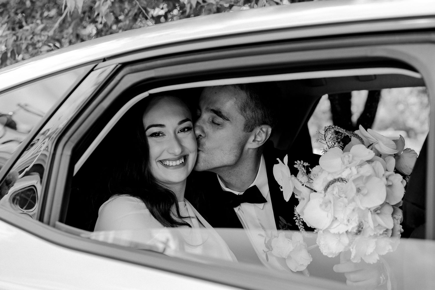 Wedding couple sharing joyful moments inside vintage car.