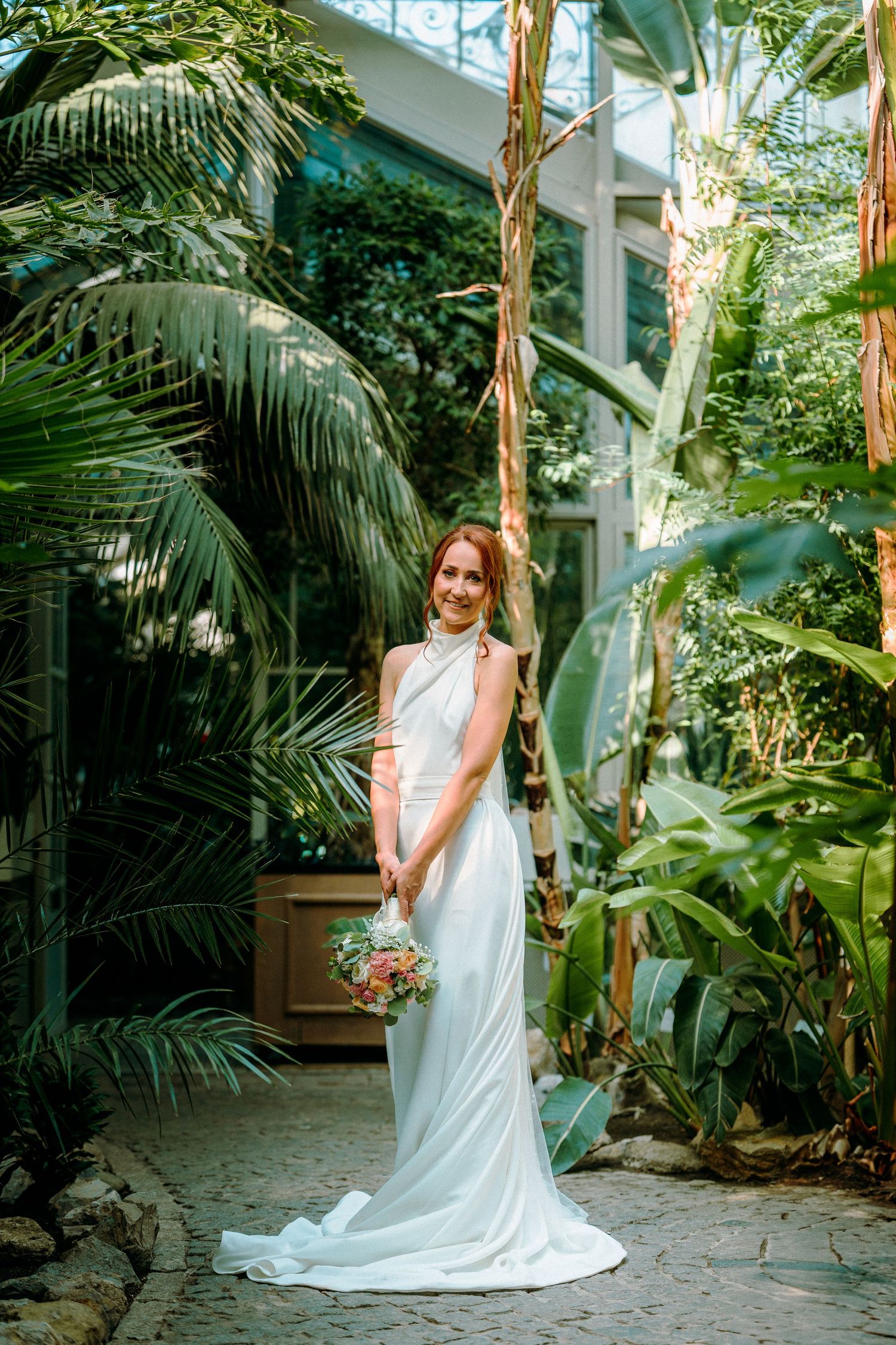 Elegant wedding photos taken in a greenhouse with tropical plants and natural lighting.