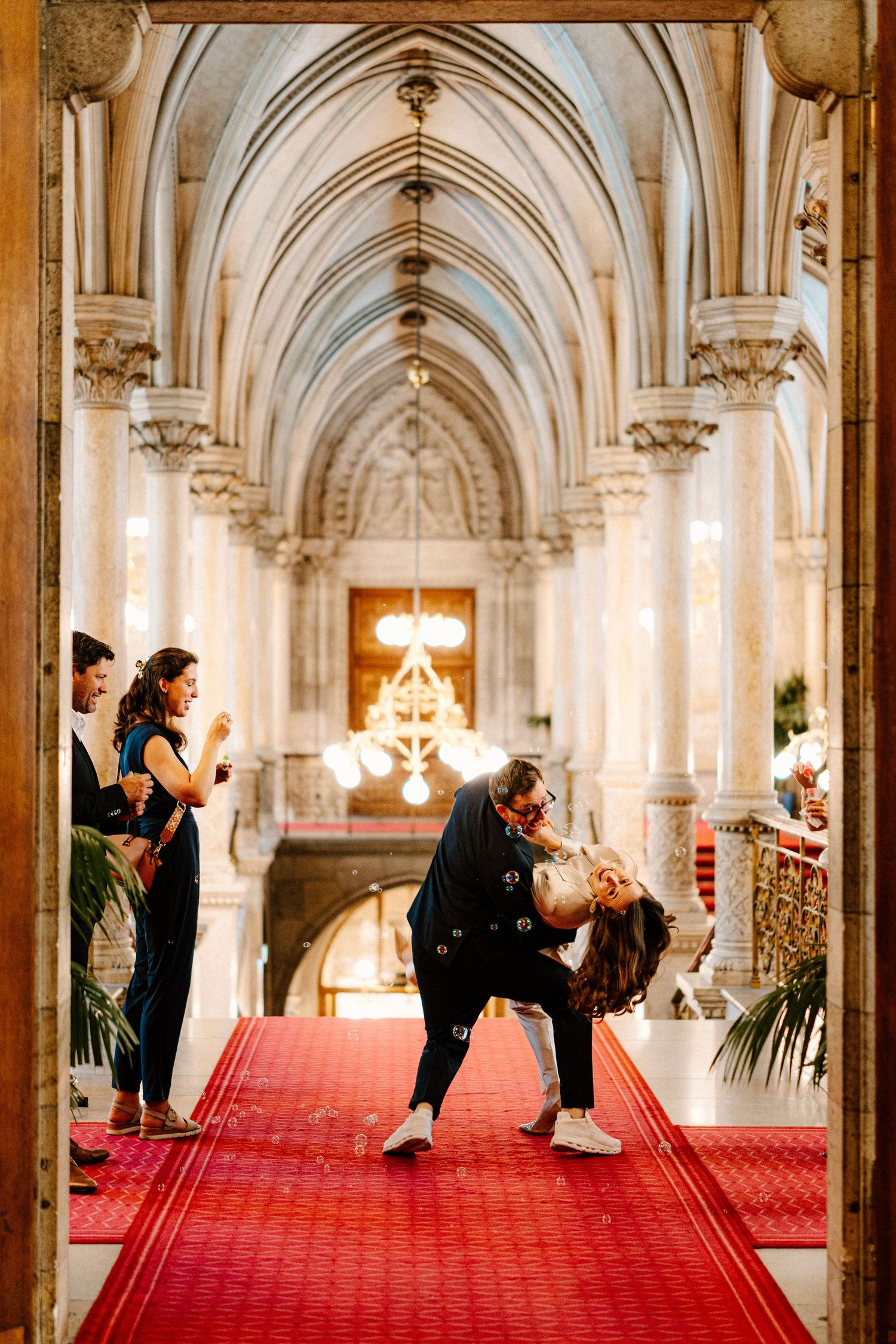 Couple performs romantic dips in a grand gothic cathedral hallway with red carpet.