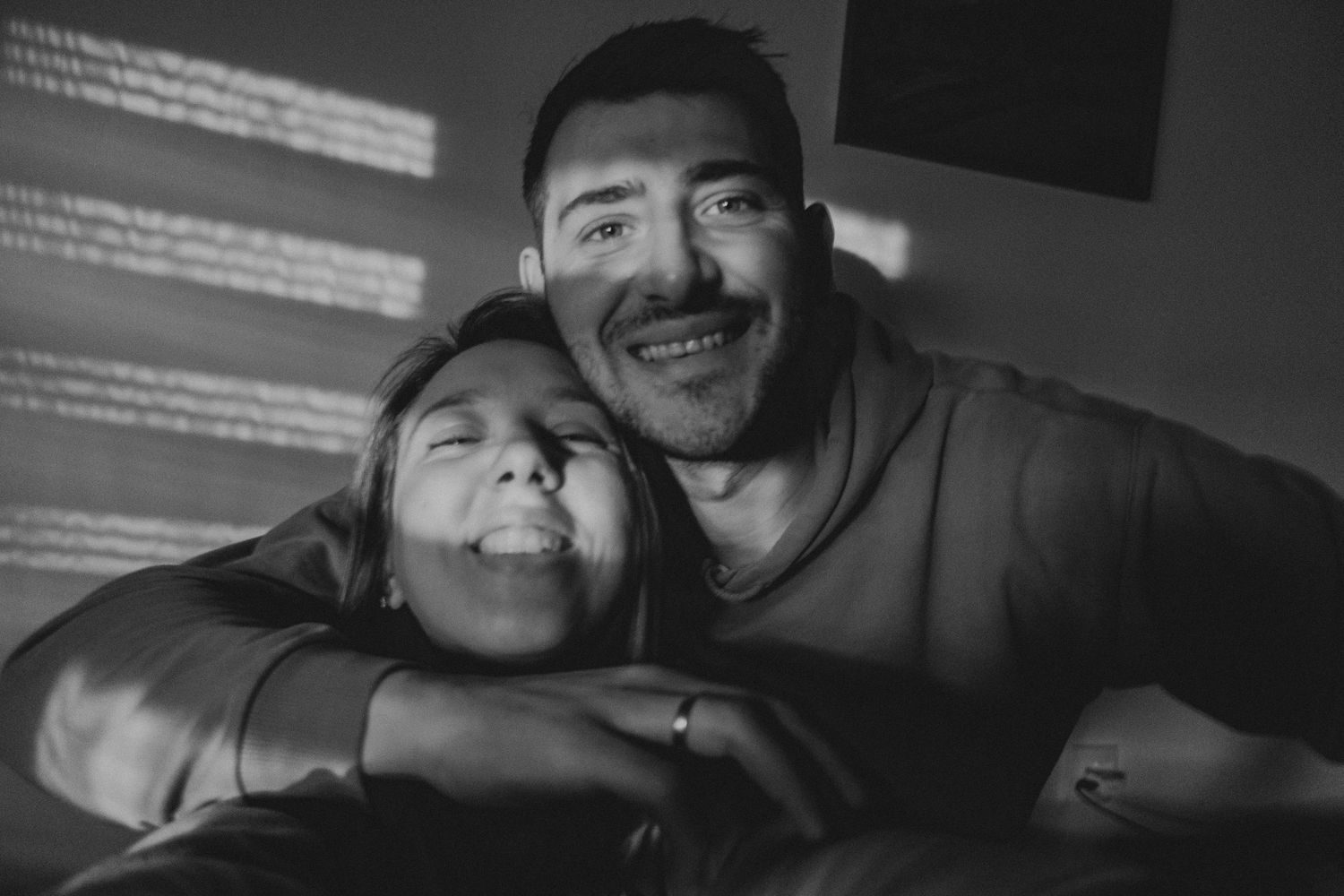 A candid black and white photograph showing people sharing a joyful moment together.