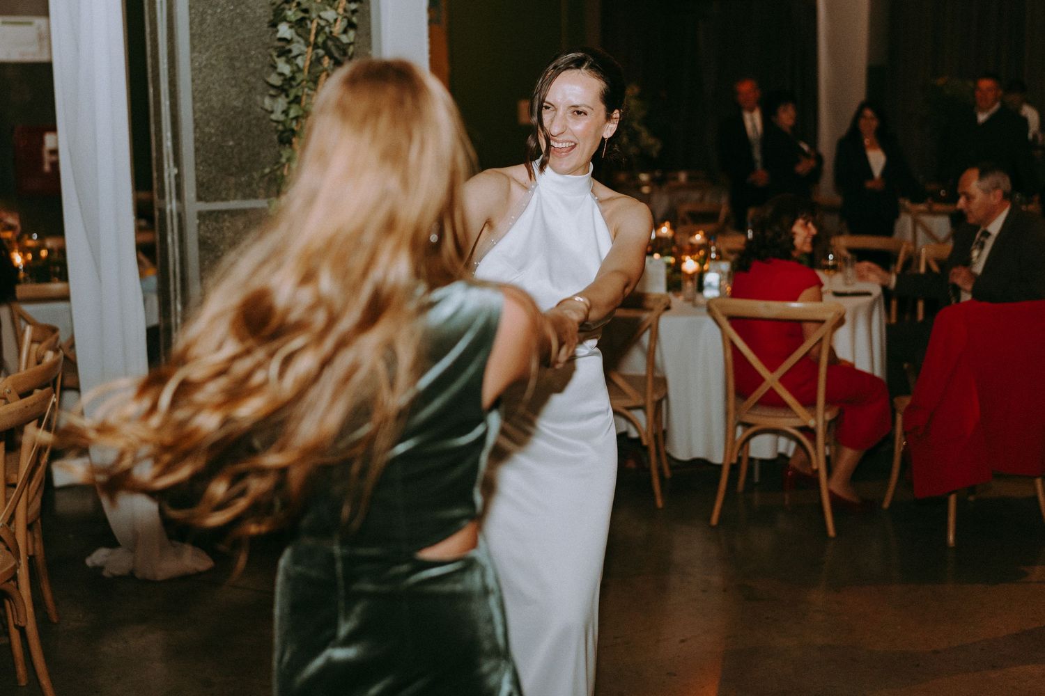 Wedding reception dance floor scene with guests celebrating in warm lighting.