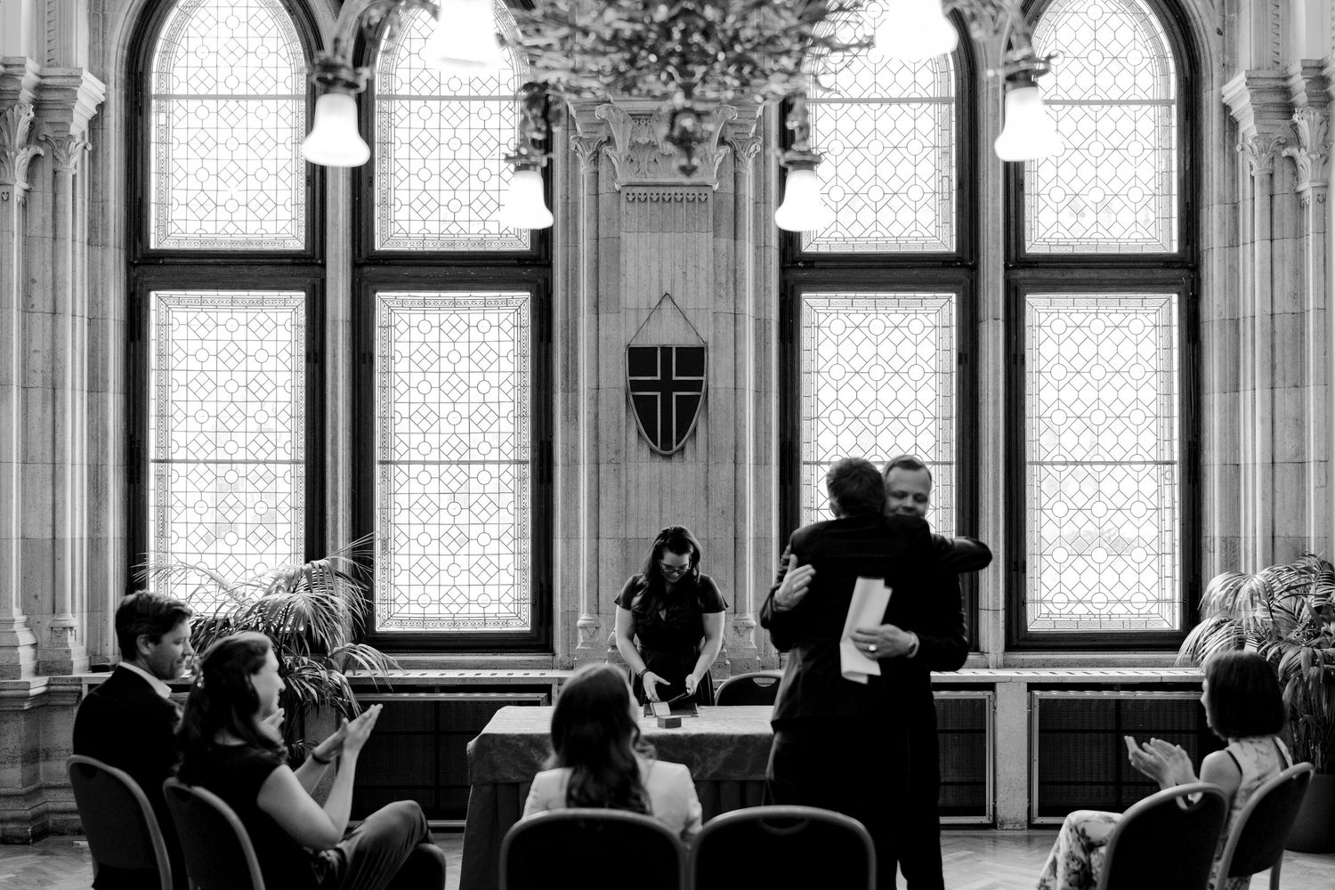 Gothic arched windows and ornate architecture frame an elegant indoor gathering.