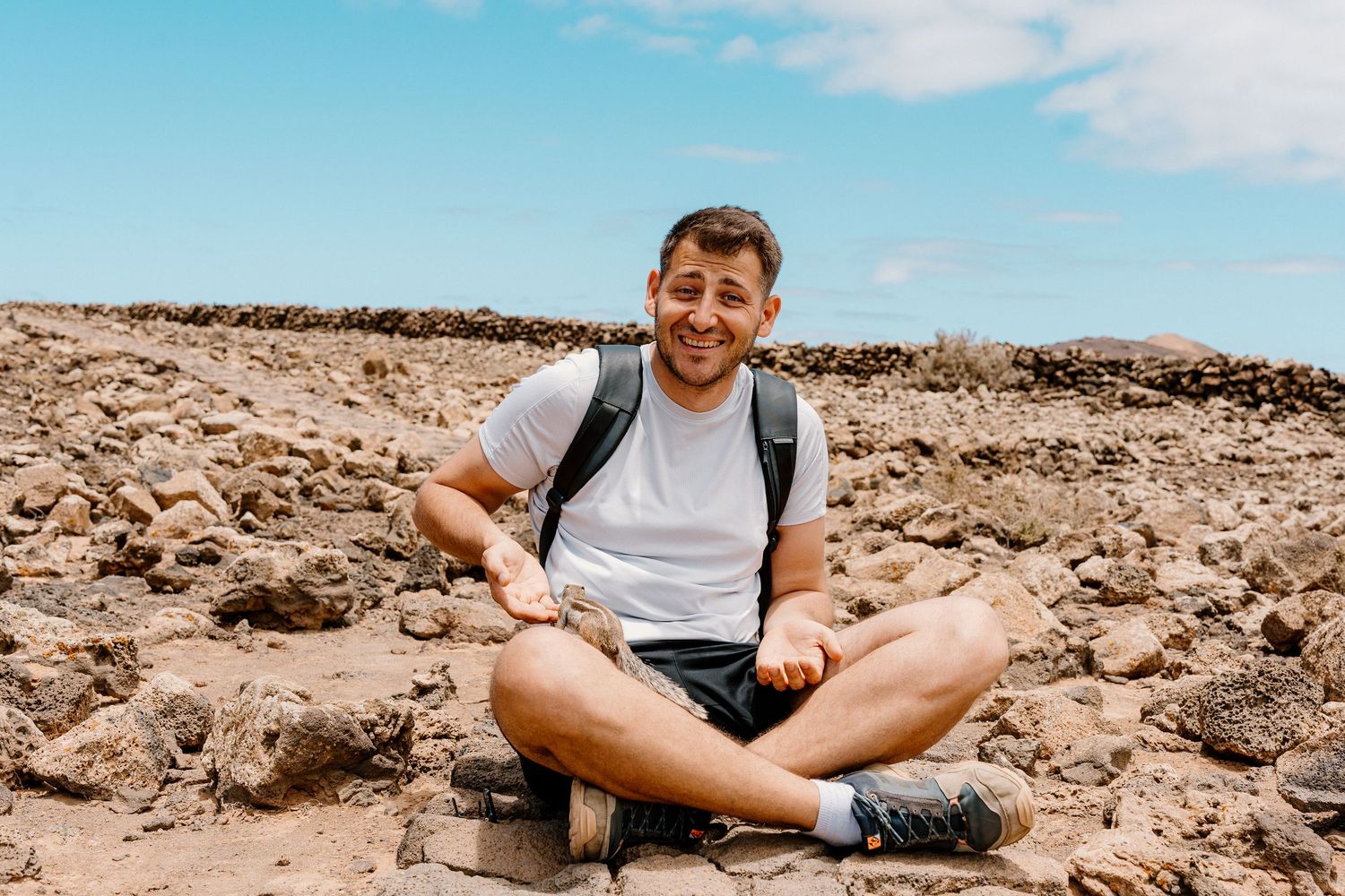 A person sitting on rocky coastal terrain with ocean views.