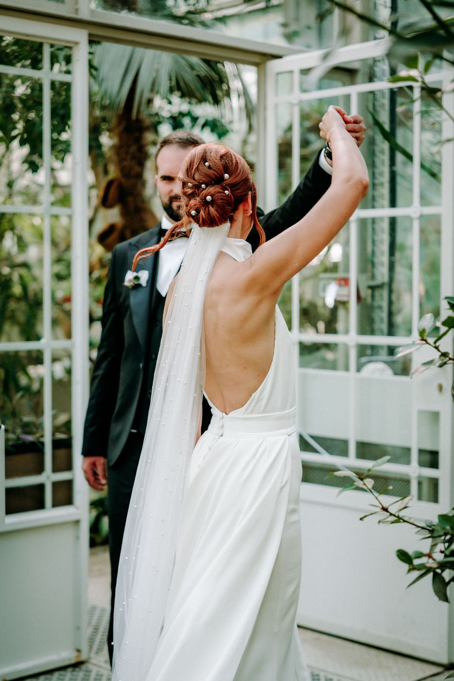Wedding celebration in a greenhouse with white dress and formal attire.