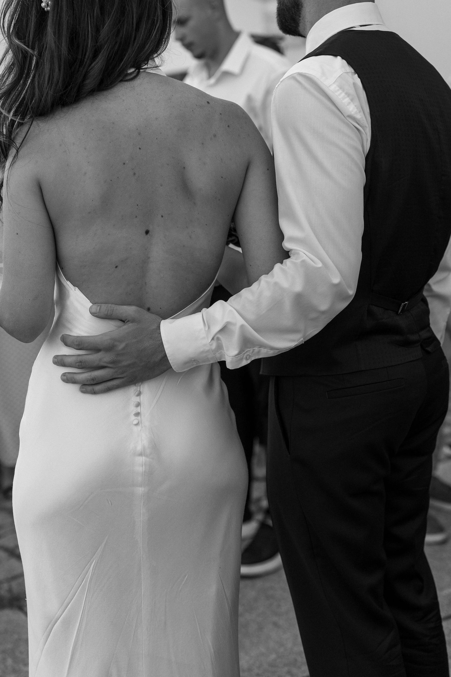 Intimate moment captured showing back detail of bride's elegant fitted dress.