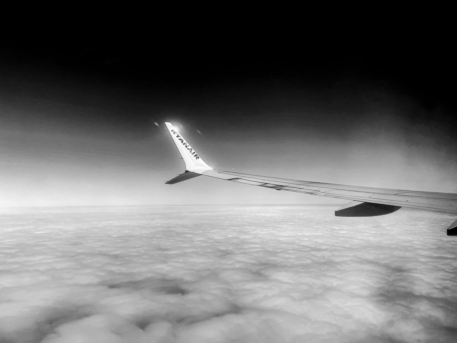 Aerial view of clouds from airplane window in black and white.