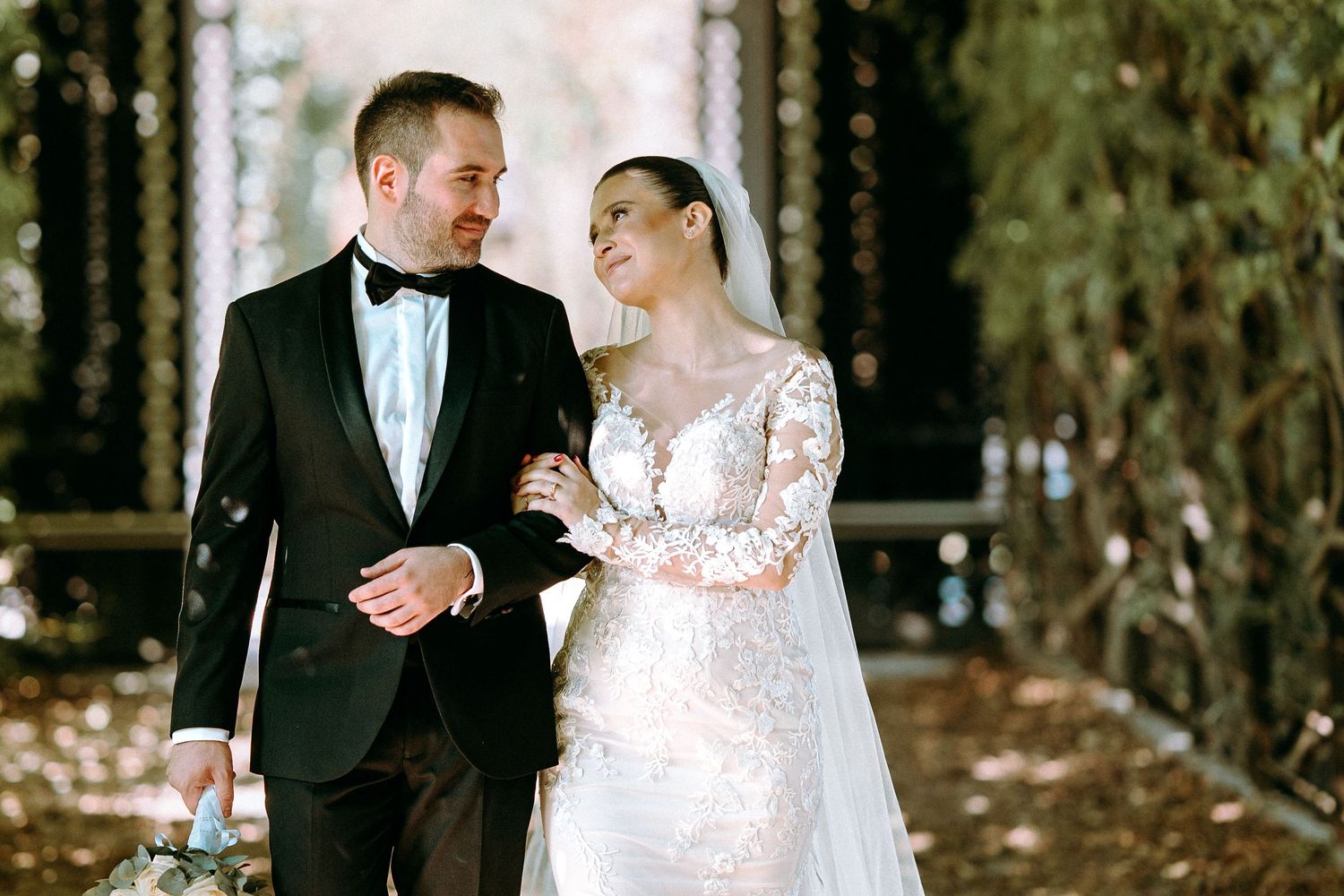 A couple sharing an intimate moment while walking together under a garden arbor.