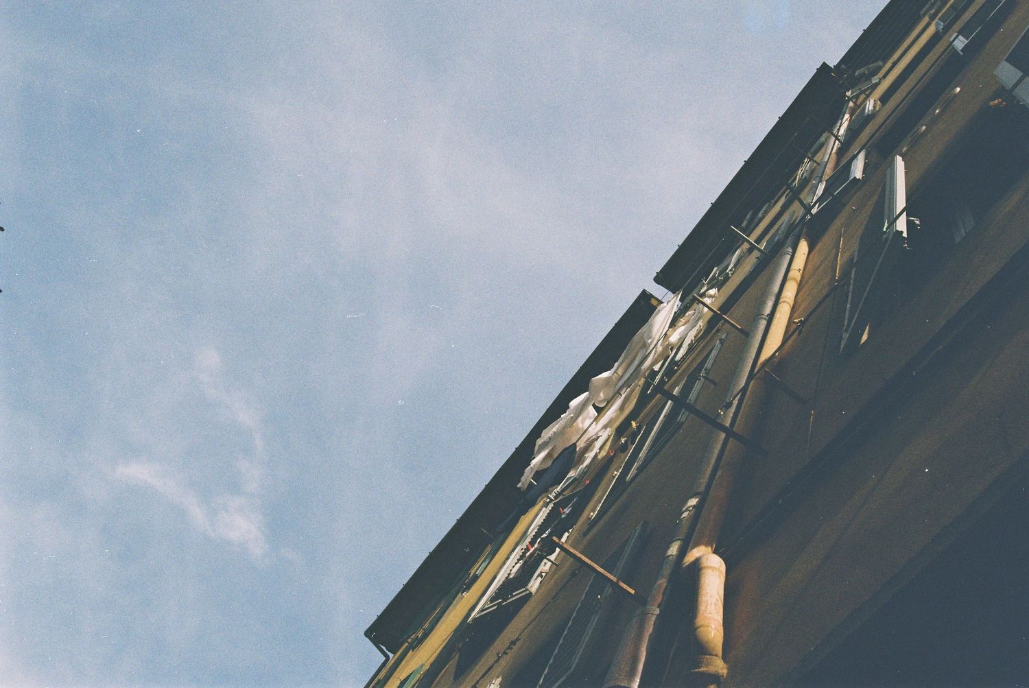 Low angle view of historic building corner with drainpipes against blue cloudy sky.